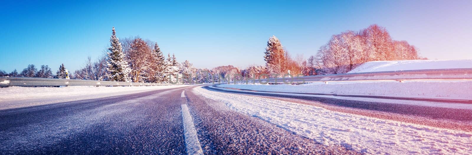 Panoramic view of the wide snowy road in winter. Scenery background of the asphalt highway.