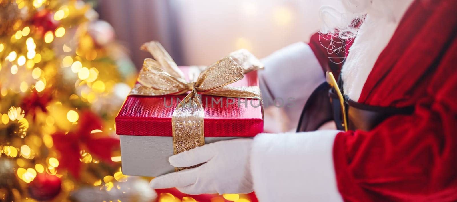 View of hands of Santa Claus with giftbox in his hans indoors. Concept of Christmas and New Year.