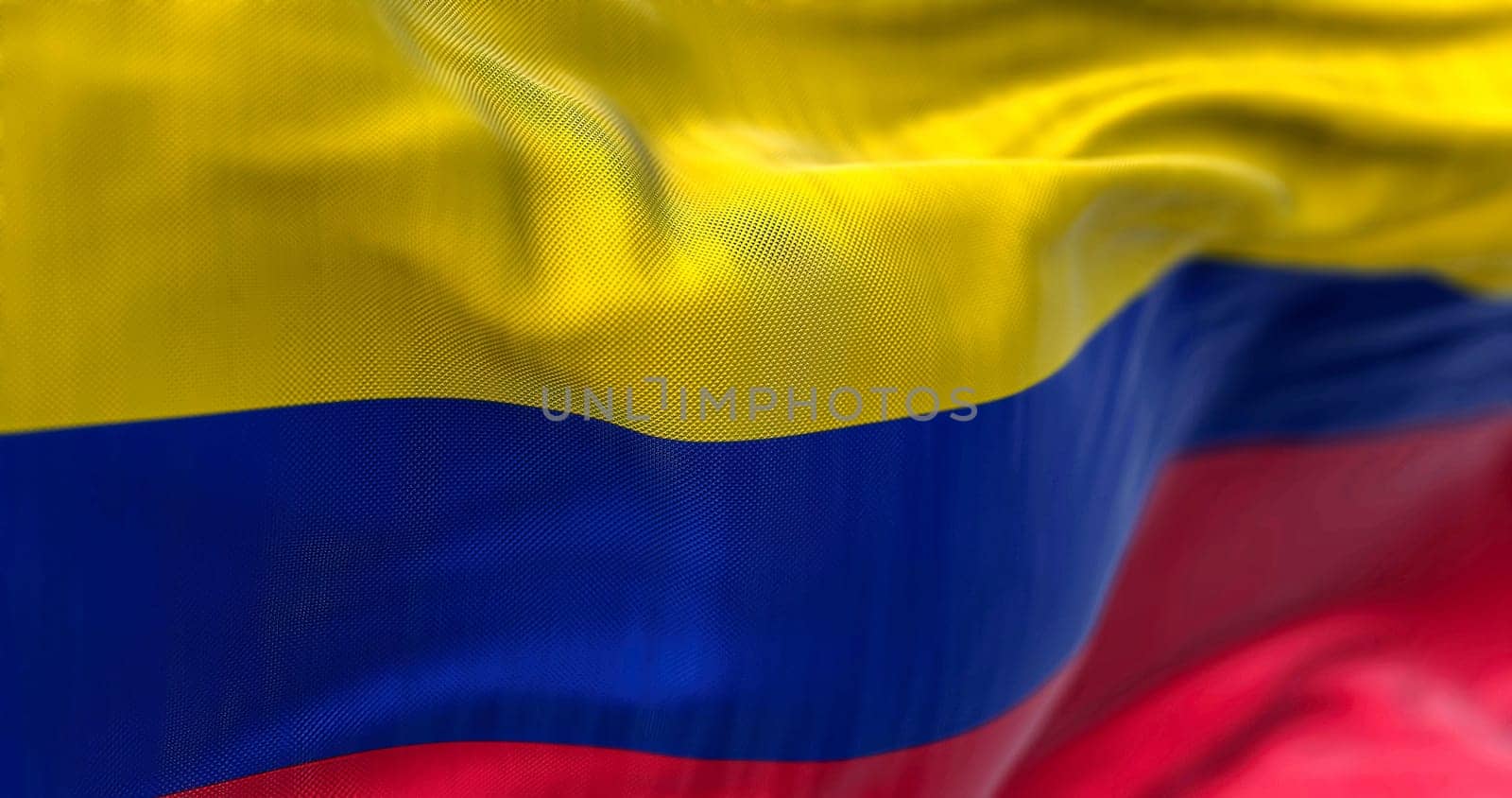 Close-up view of Colombia National flag waving. The Republic of Colombia is a state in the north-western region of South America. Fabric textured background. Selective focus