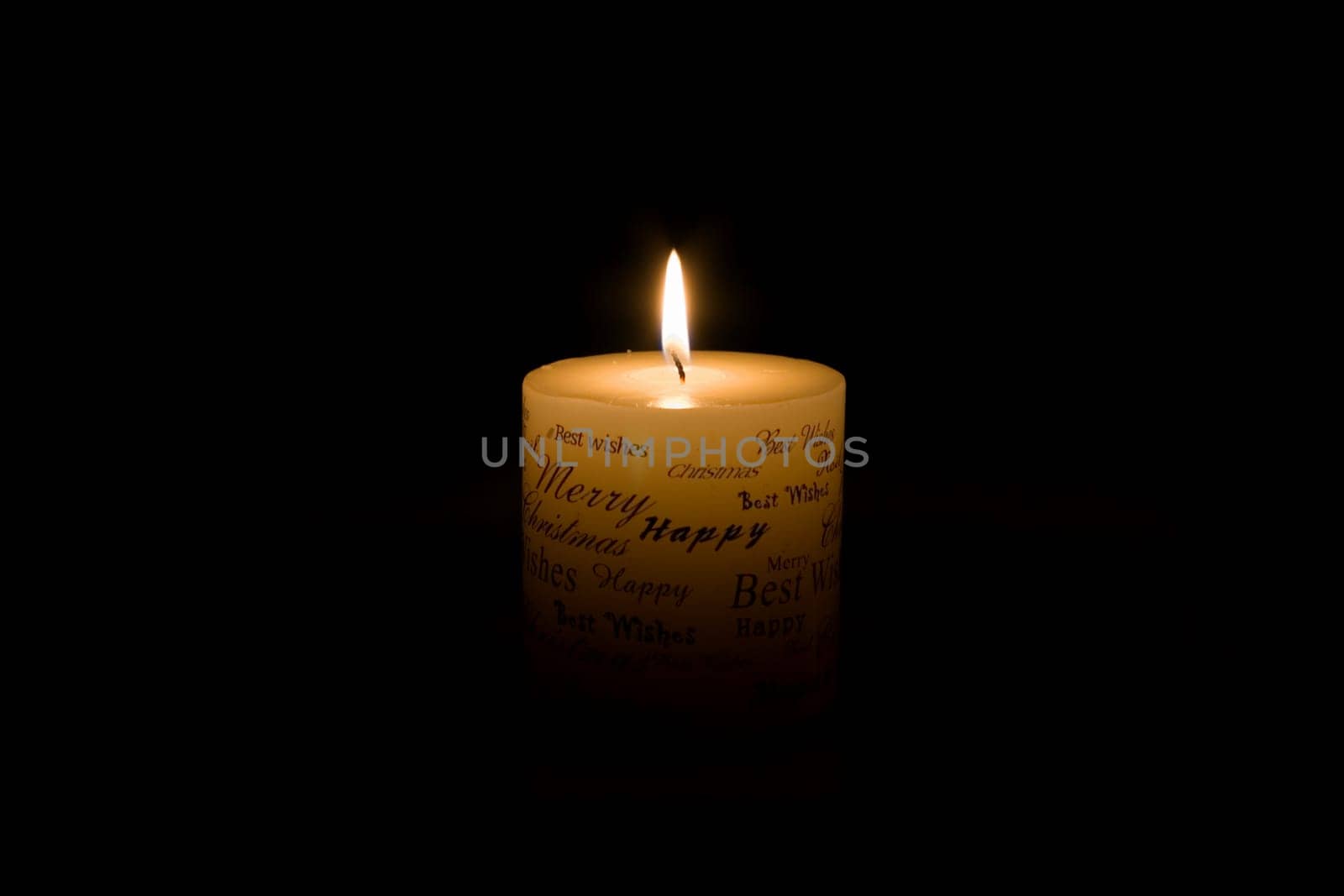 White Christmas candle lit on black background