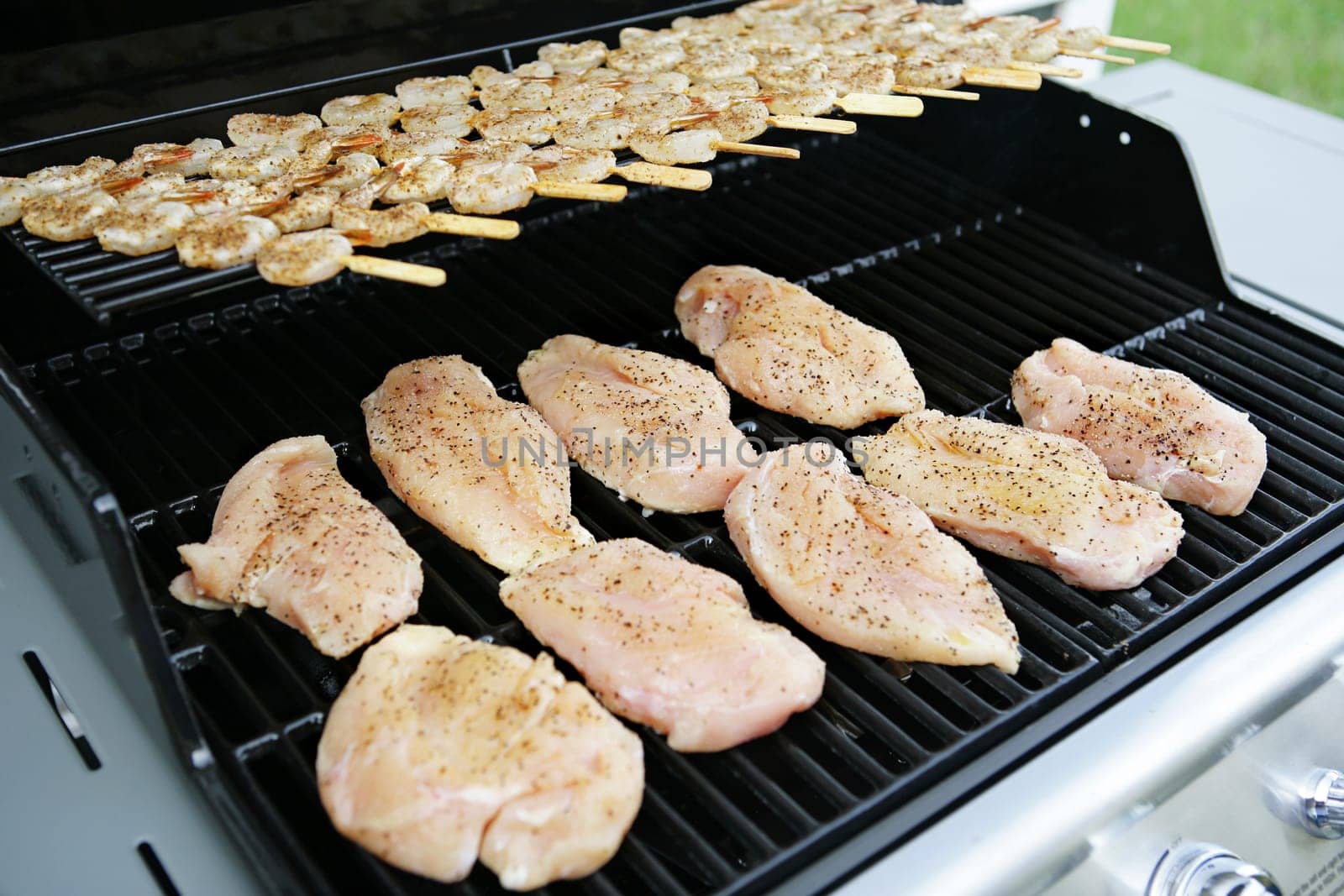 Chicken and shrimp cooking on at backyard barbecue grill.