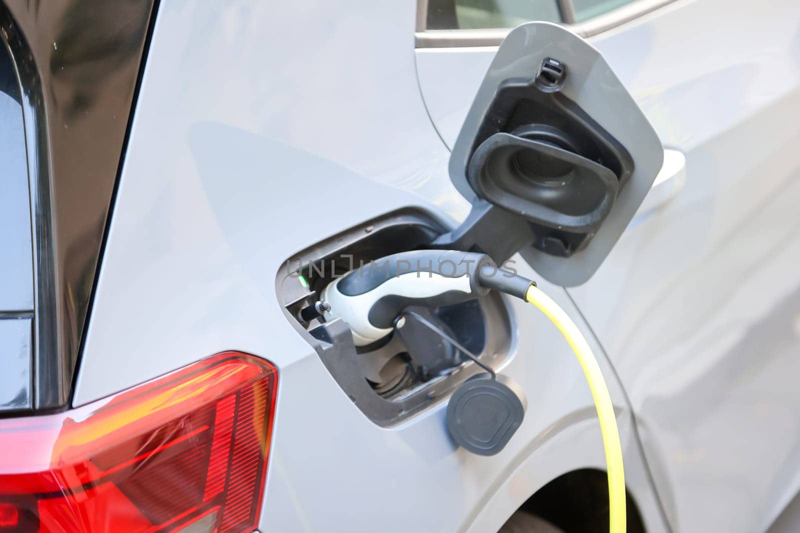 An electric car is charged at a charging station using a charging cable.