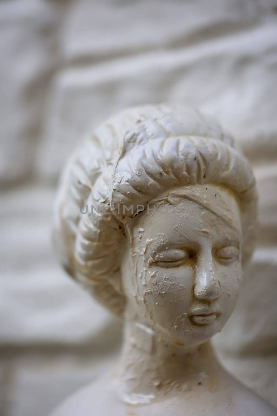 The head of a restored female figure on a white stone wall.
