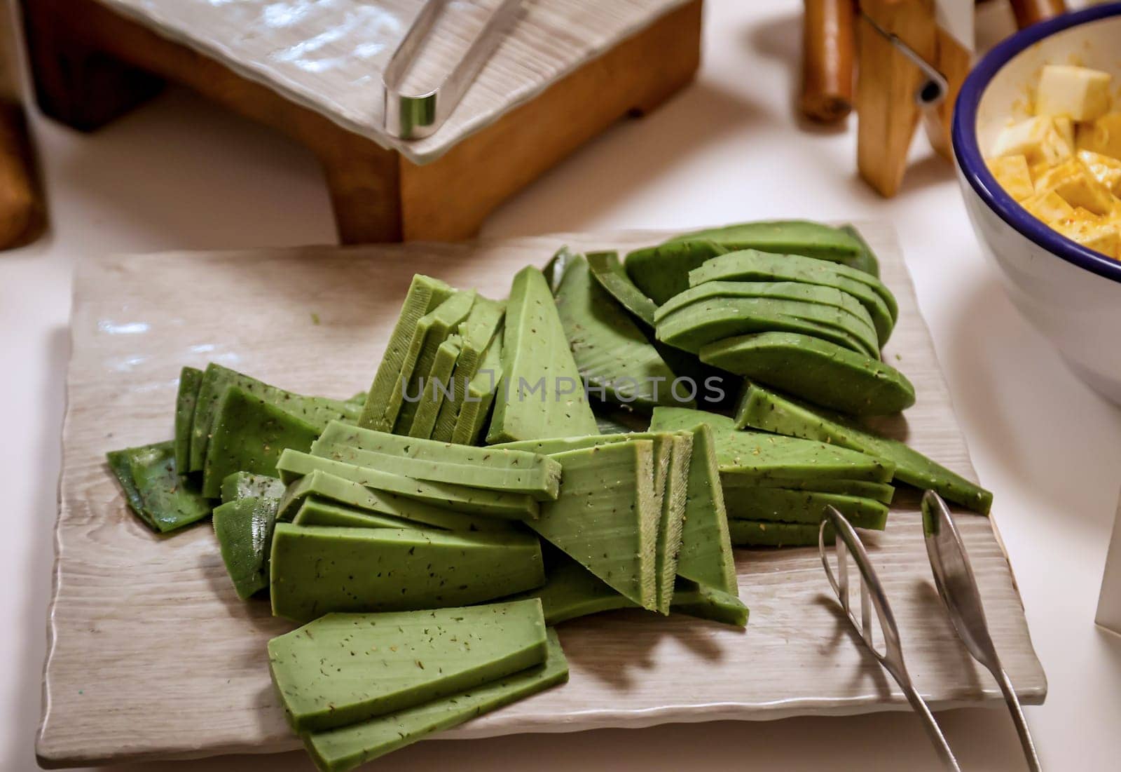 Many green yellow slices of cheese on a platter.