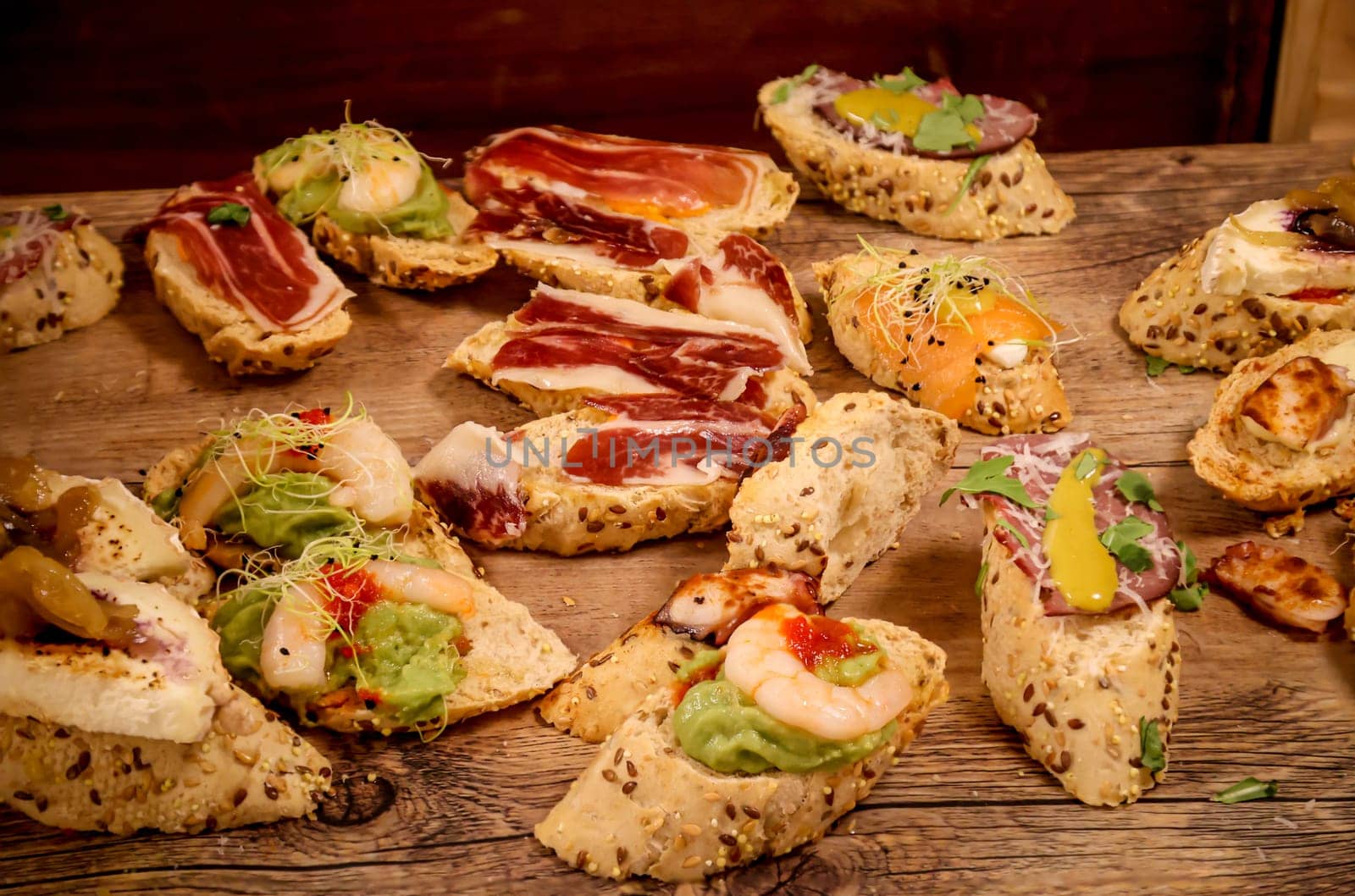 Many tapas, small baguettes pieces with toppings on a board.