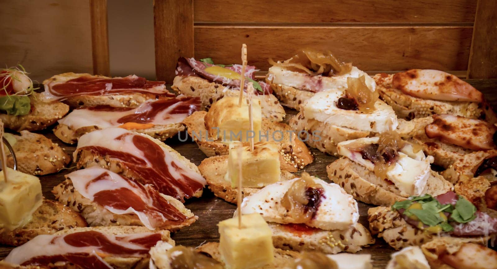 Many tapas, small baguettes pieces with toppings on a board.