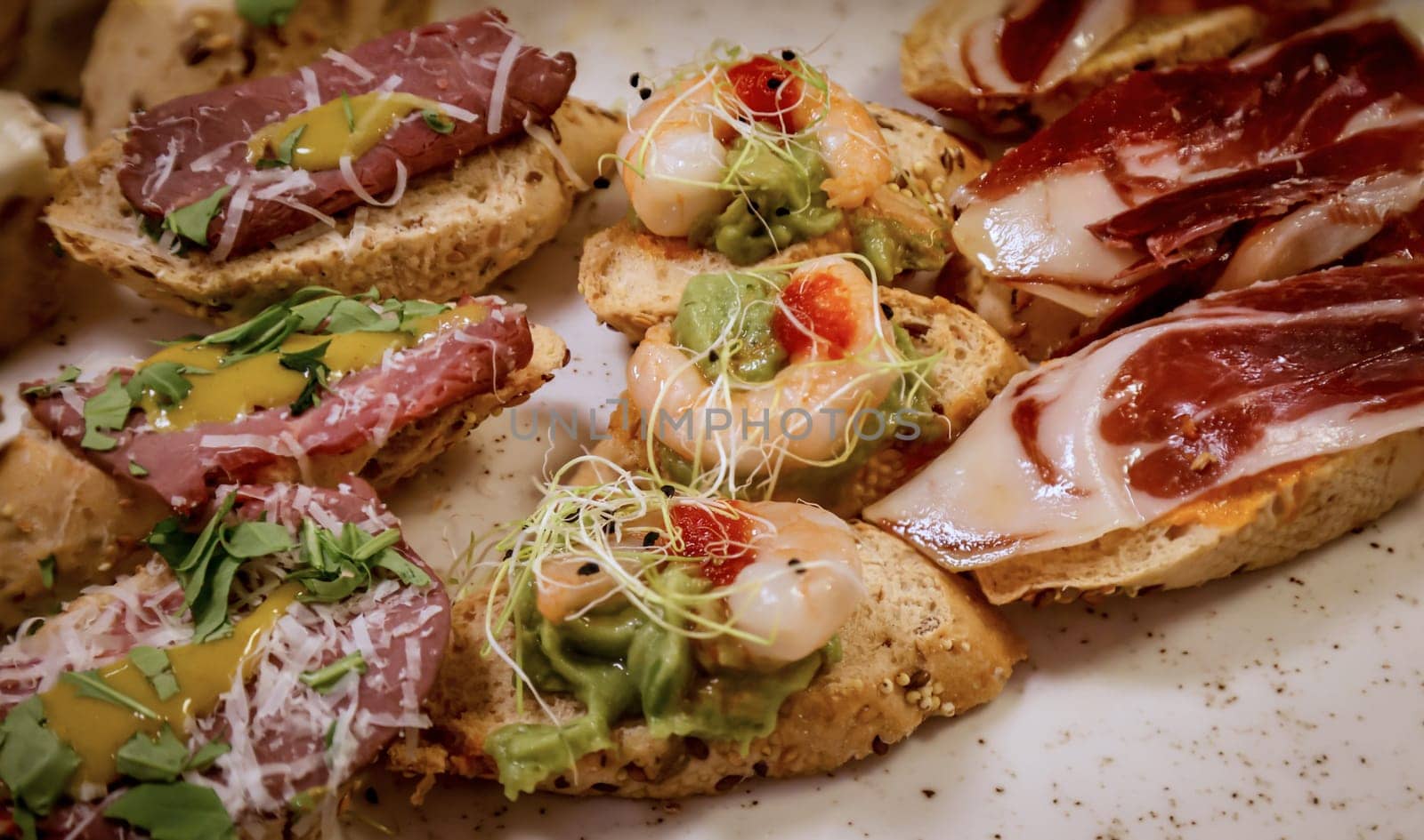 Many tapas, small baguettes pieces with toppings on a board.