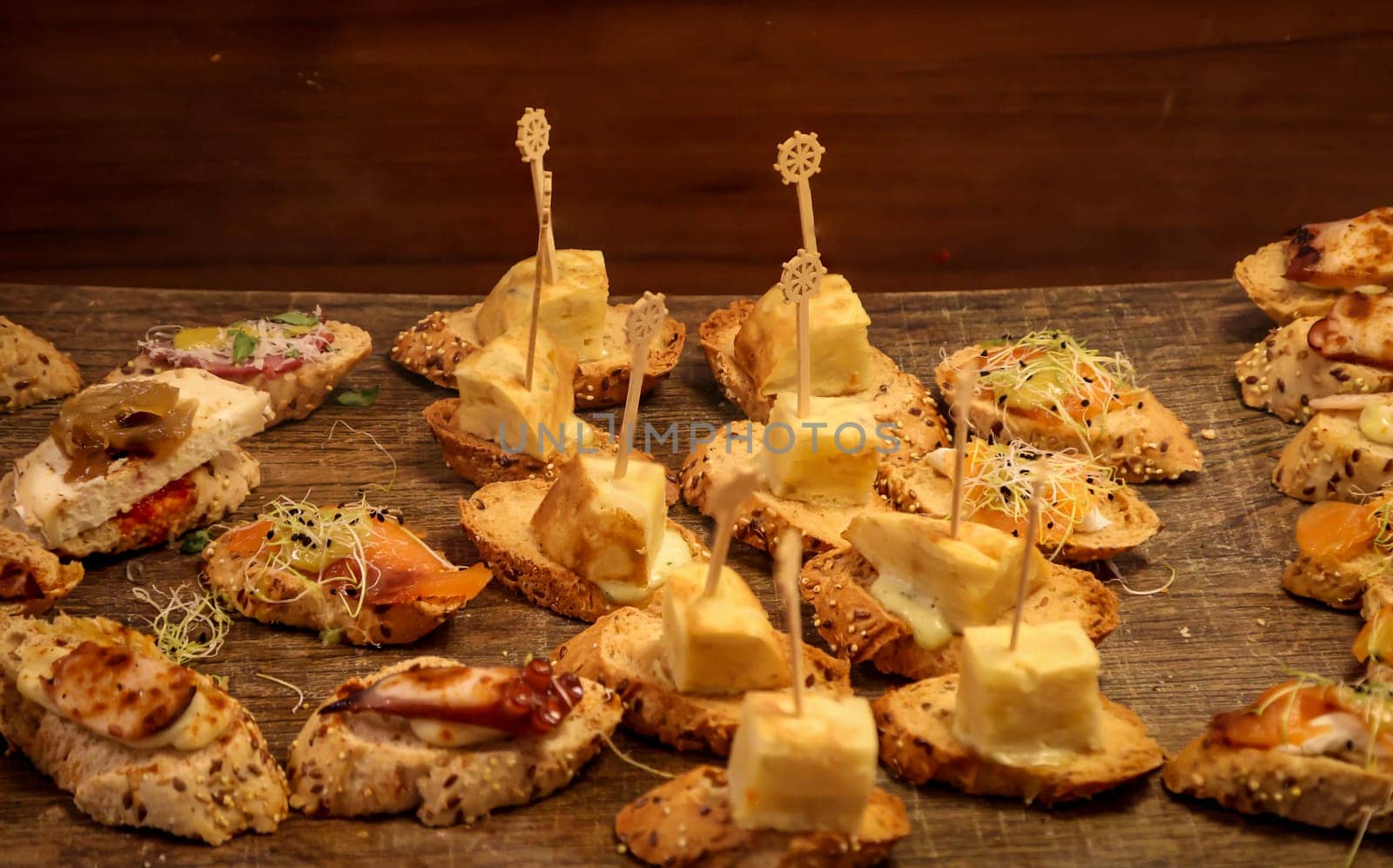 Many tapas, small baguettes pieces with toppings on a board.