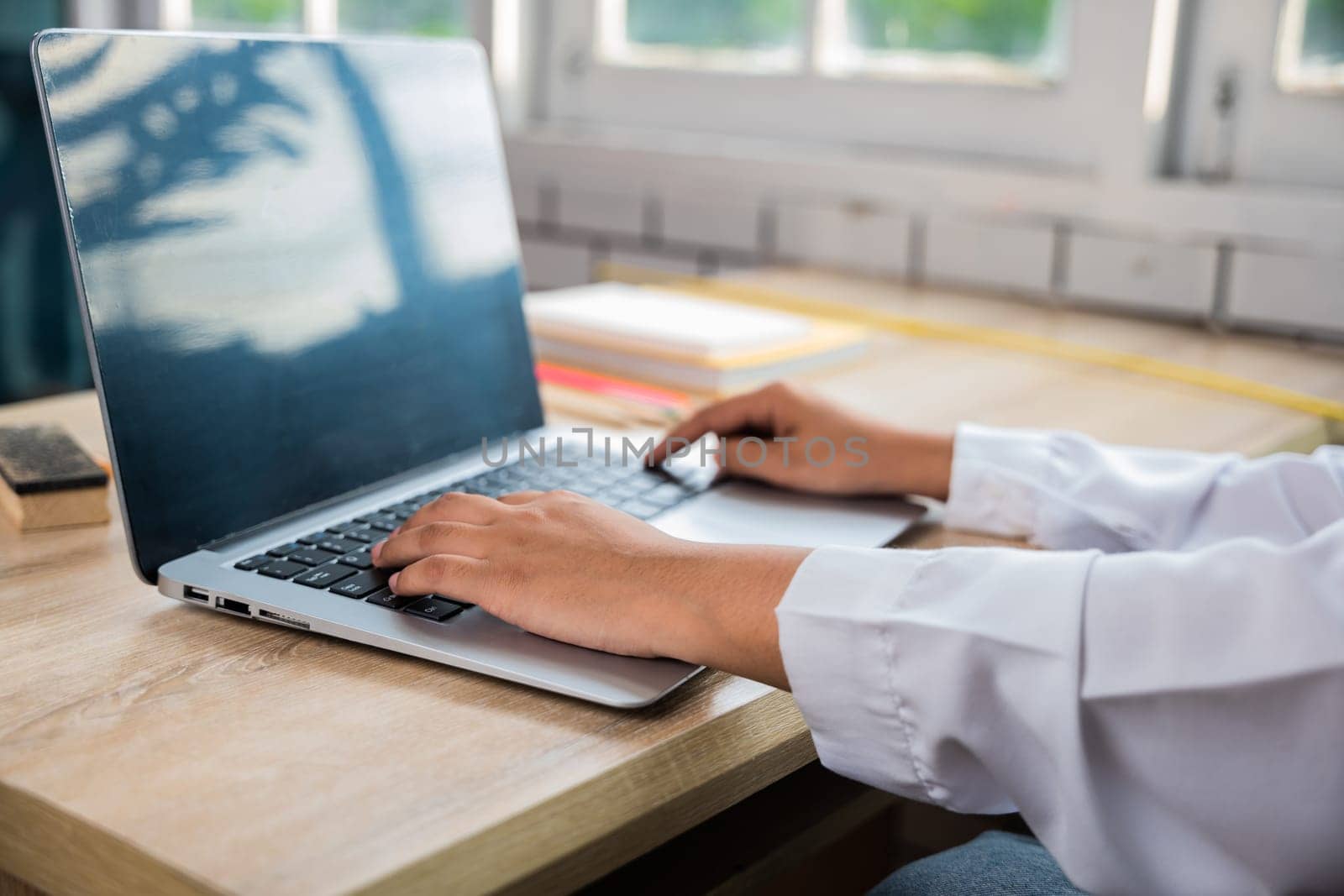 Back to school. Close up hands of female using computer sitting at school table, Young woman teacher with laptop at desk in classroom, Online education and technology learning concept