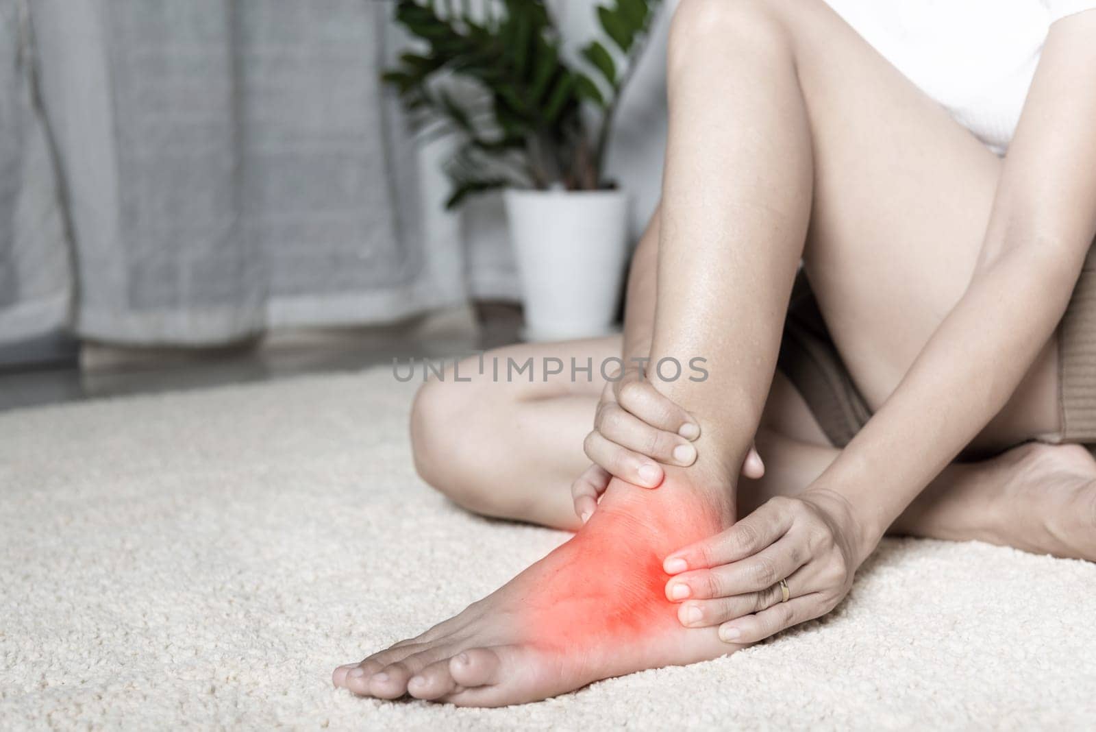 Foot pain, Woman holds her ankle injury feeling pain in her foot at home, female suffering from feet ache use hand massage relax muscle from ankle in home interior, Healthcare problems and medical