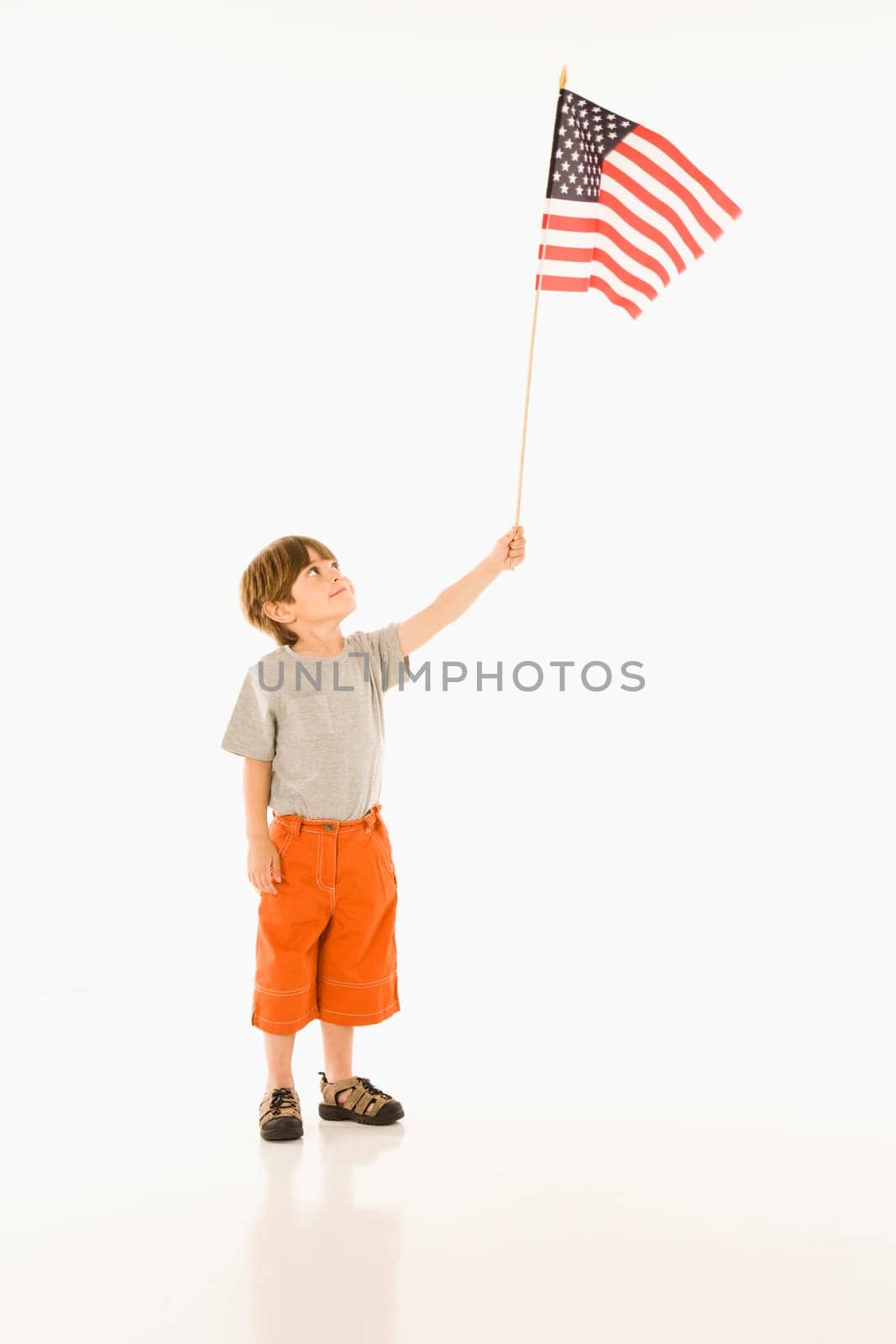 Boy holding American flag against white background.