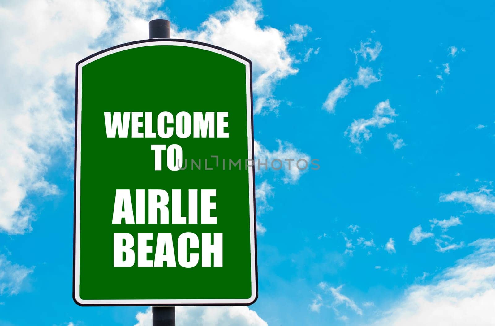 Green road sign with greeting message WELCOME TO AIRLIE BEACH isolated over clear blue sky background with available copy space. Travel destination concept  image