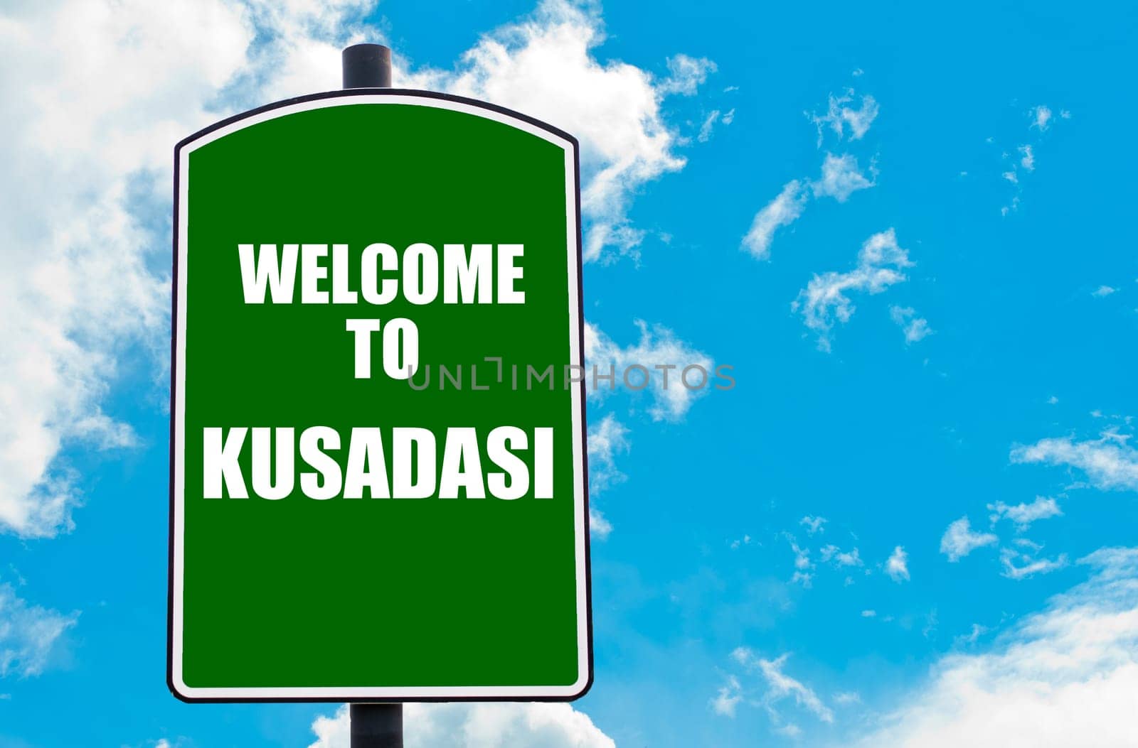 Green road sign with greeting message WELCOME TO KUSADASI isolated over clear blue sky background with available copy space. Travel destination concept  image