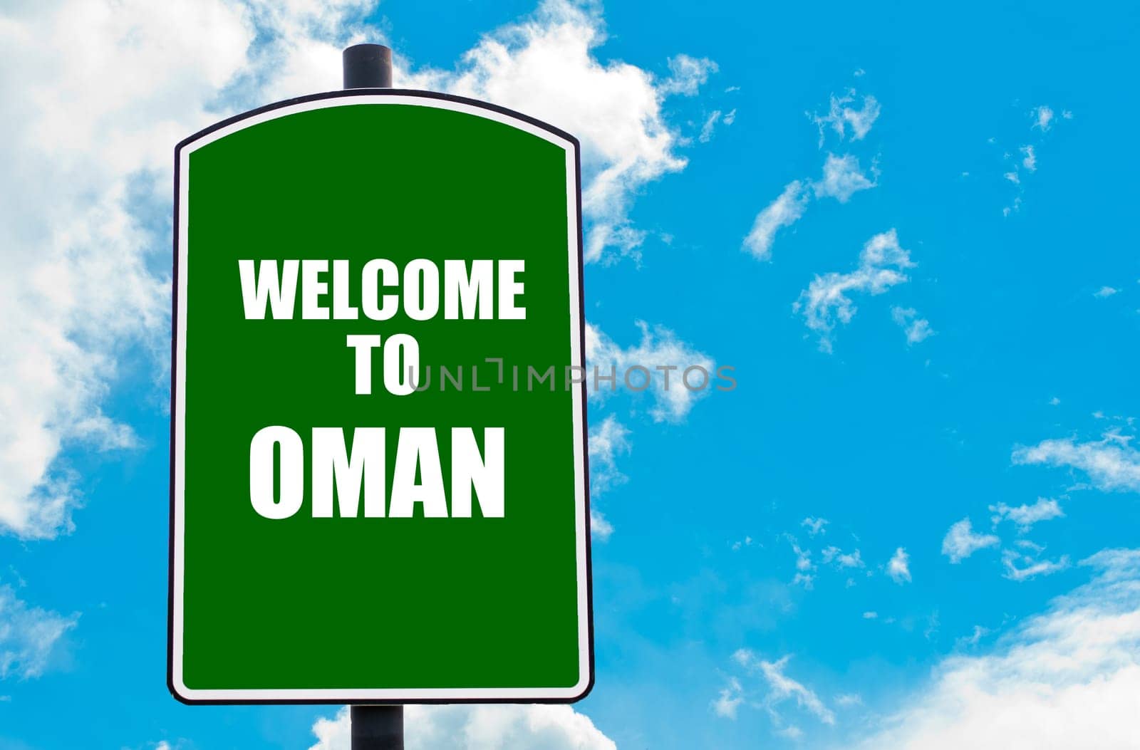 Green road sign with greeting message WELCOME TO OMAN isolated over clear blue sky background with available copy space. Travel destination concept  image