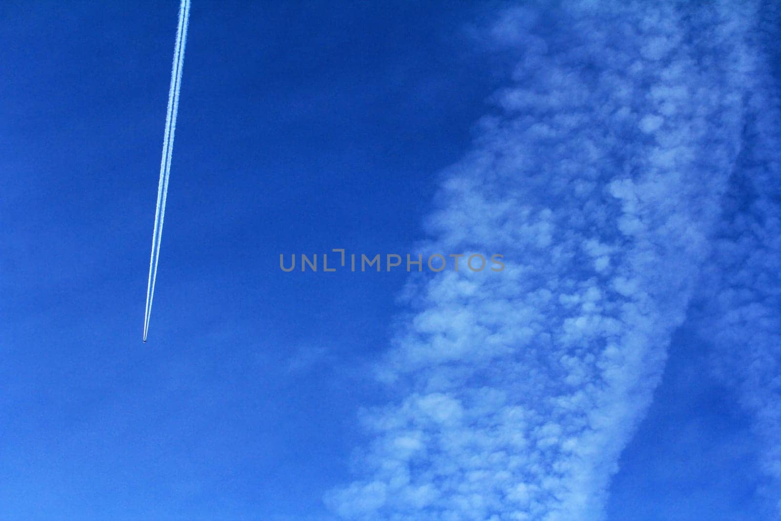 A plane with condensate stripes in the blue sky