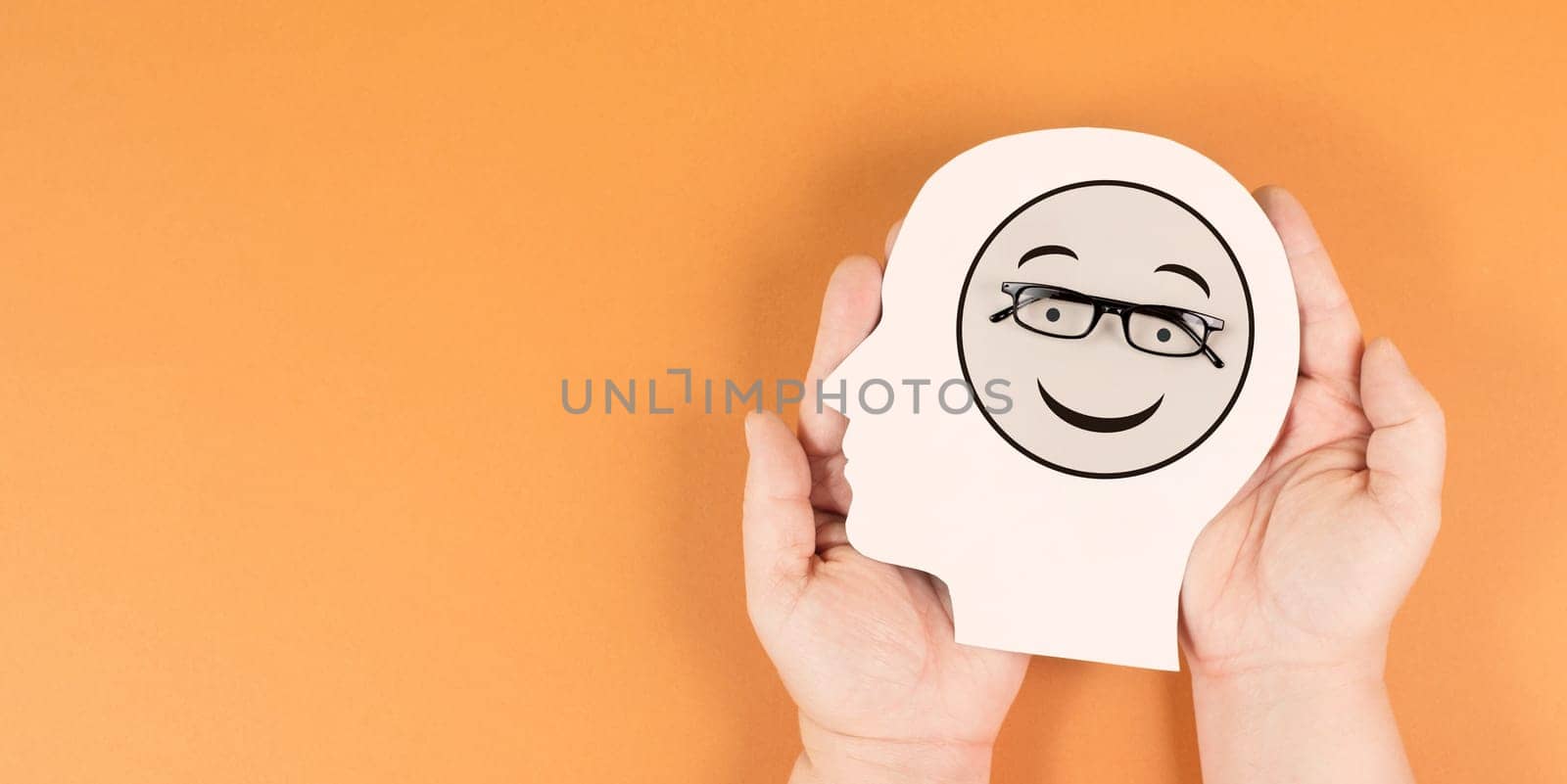 Holding a head with a happy smiling face, mental health concept, positive mindset, support and evaluation symbol