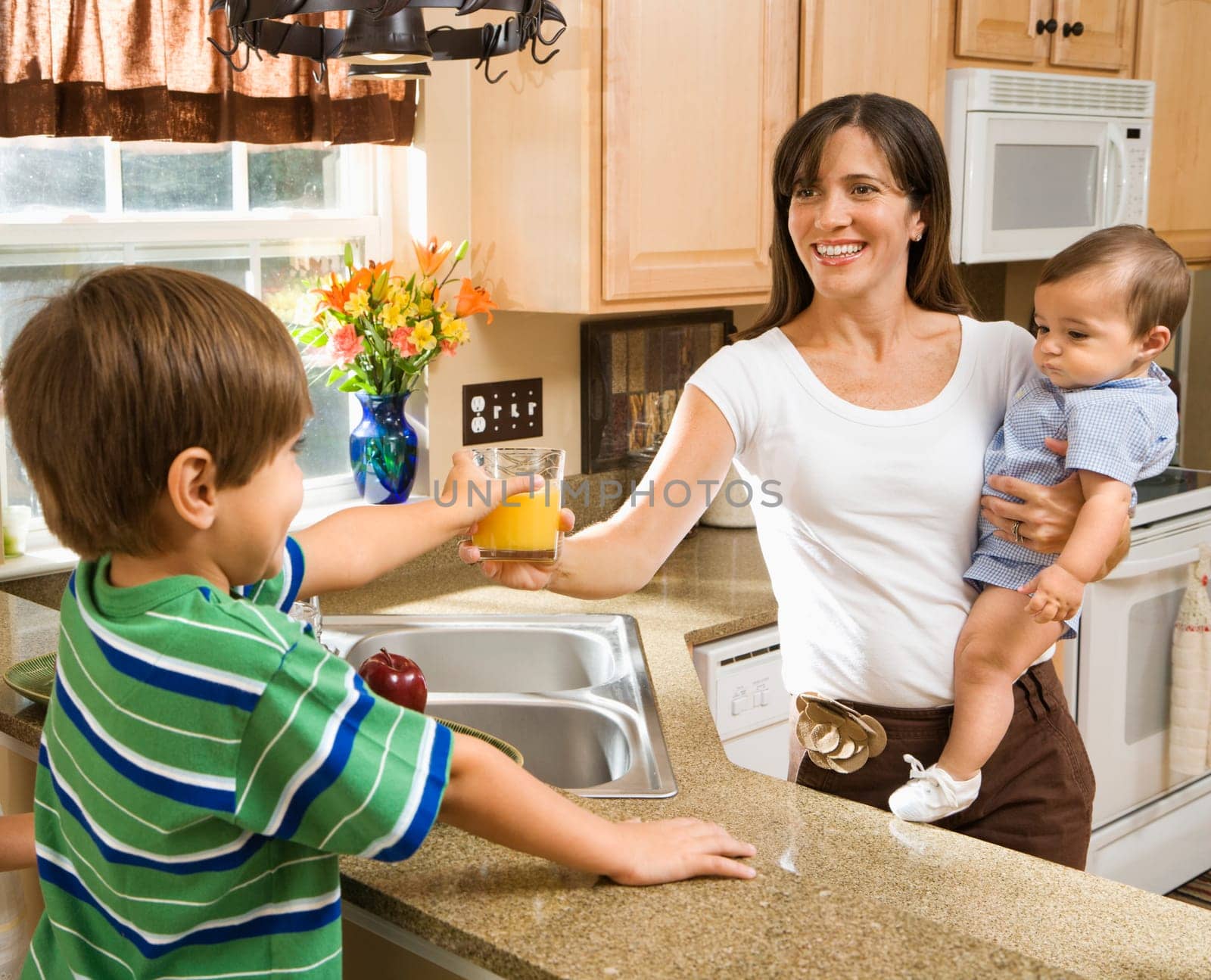 Hispanic mother and children in kitchen with juice.
