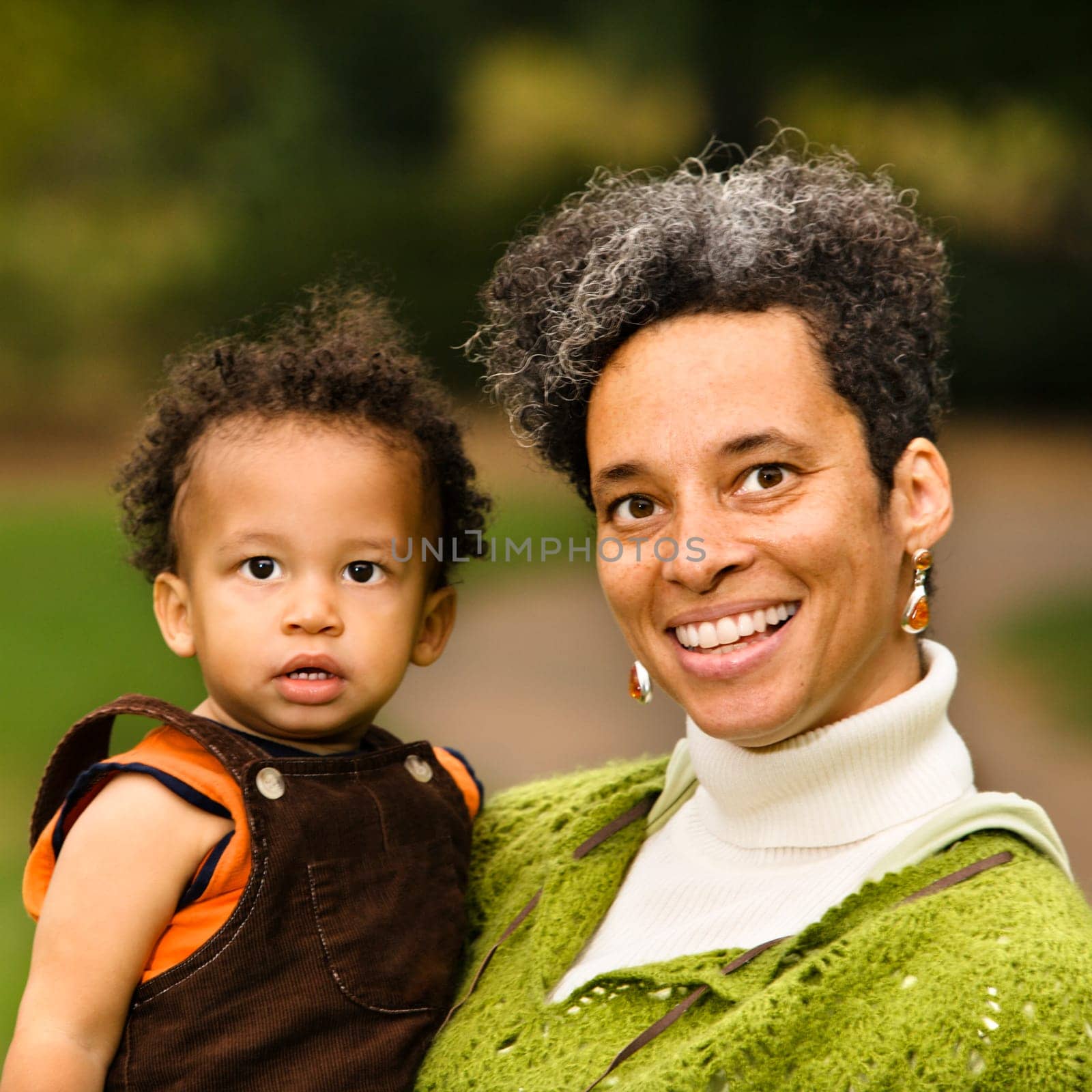 Head and shoulder portrait of woman holding boy and smiling.