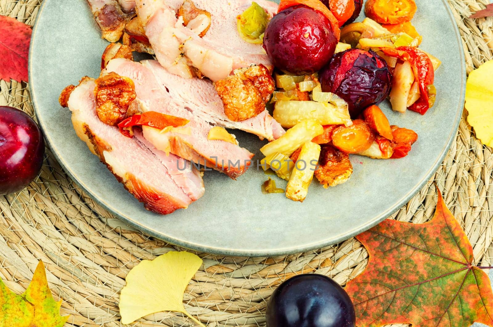 Piece of pork shoulder baked in the oven with vegetables and plums.