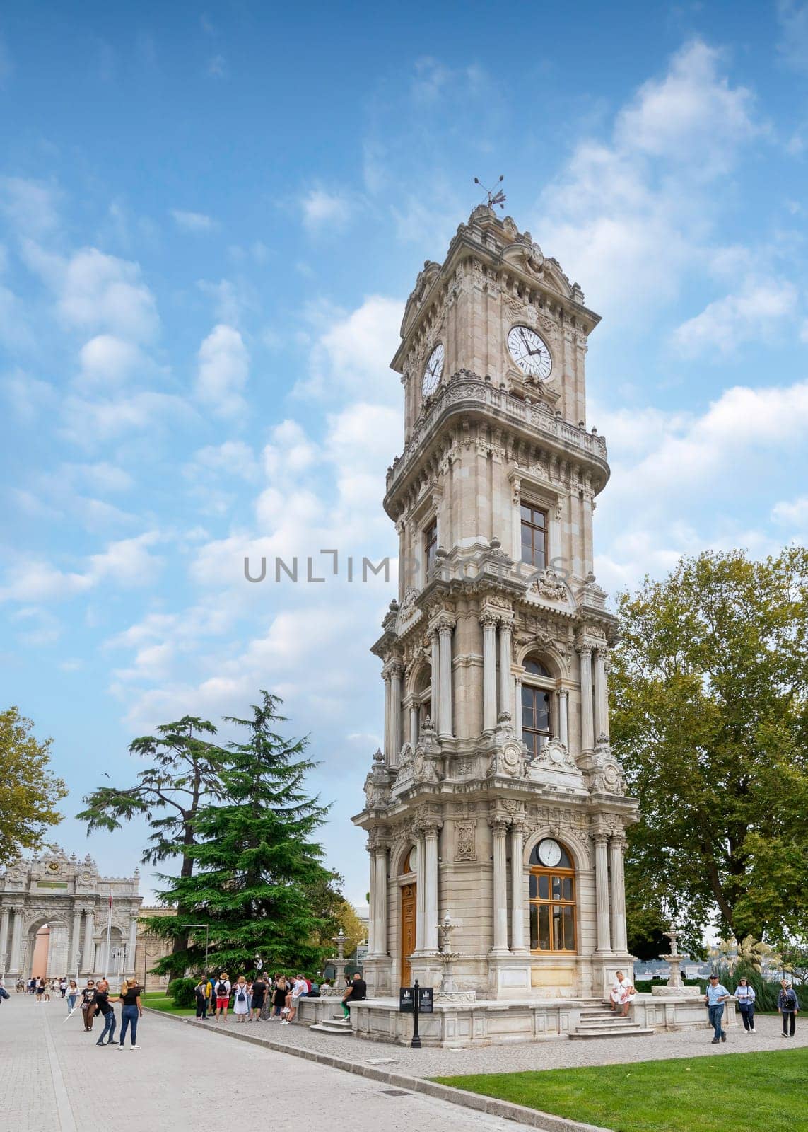 Istanbul, Turkey - August 31, 2022: Dolmabahce Clock Tower, Turkish: Dolmabahce Saat Kulesi, situated outside Dolmabahce Palace, with tourists visiting the place, and taking memorial photos