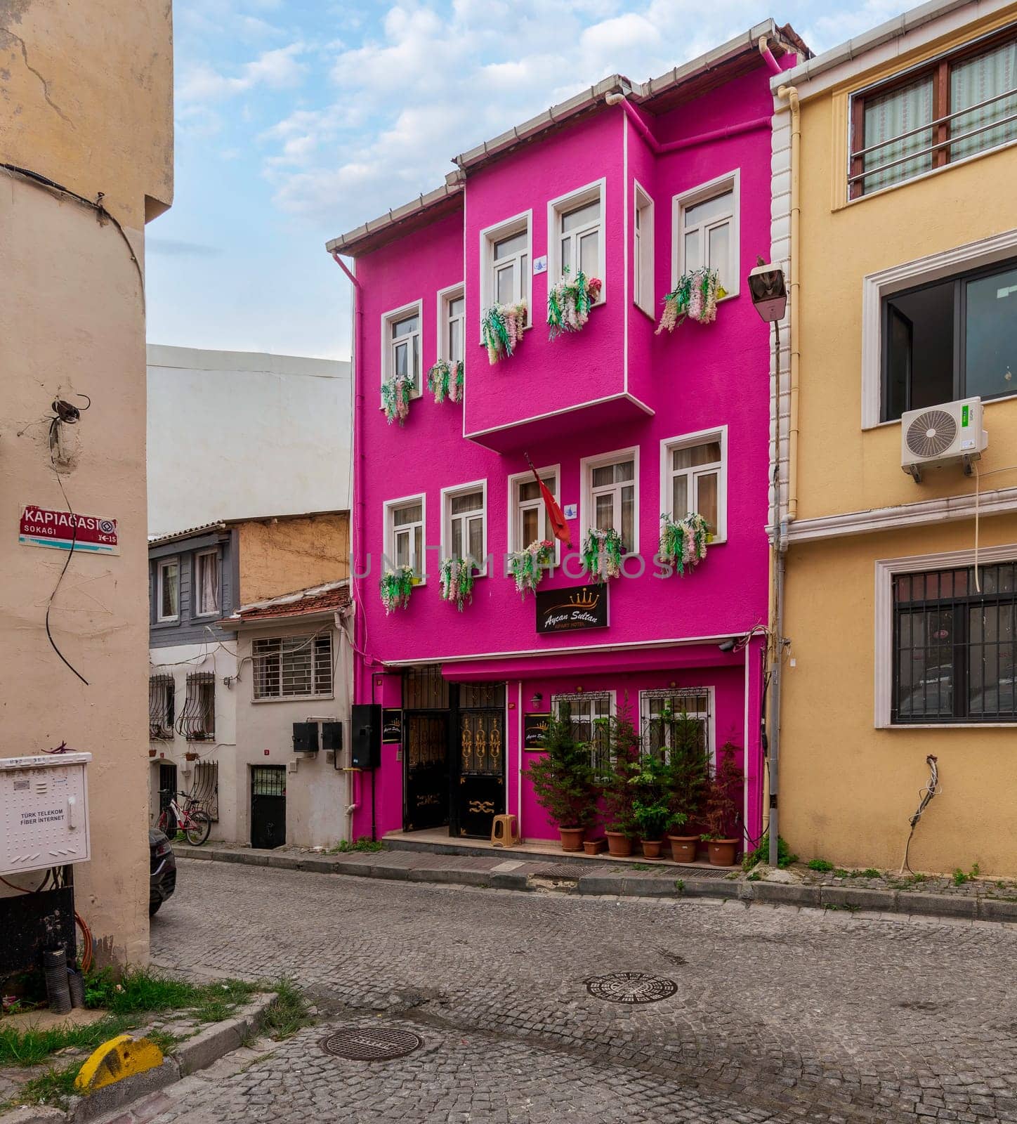 Cobblestone alley, with beautiful old colorful traditional houses, painted in pink and yellow, suited in Kapiagasi Street, Fatih district, Istanbul, Turkey, in a summer day