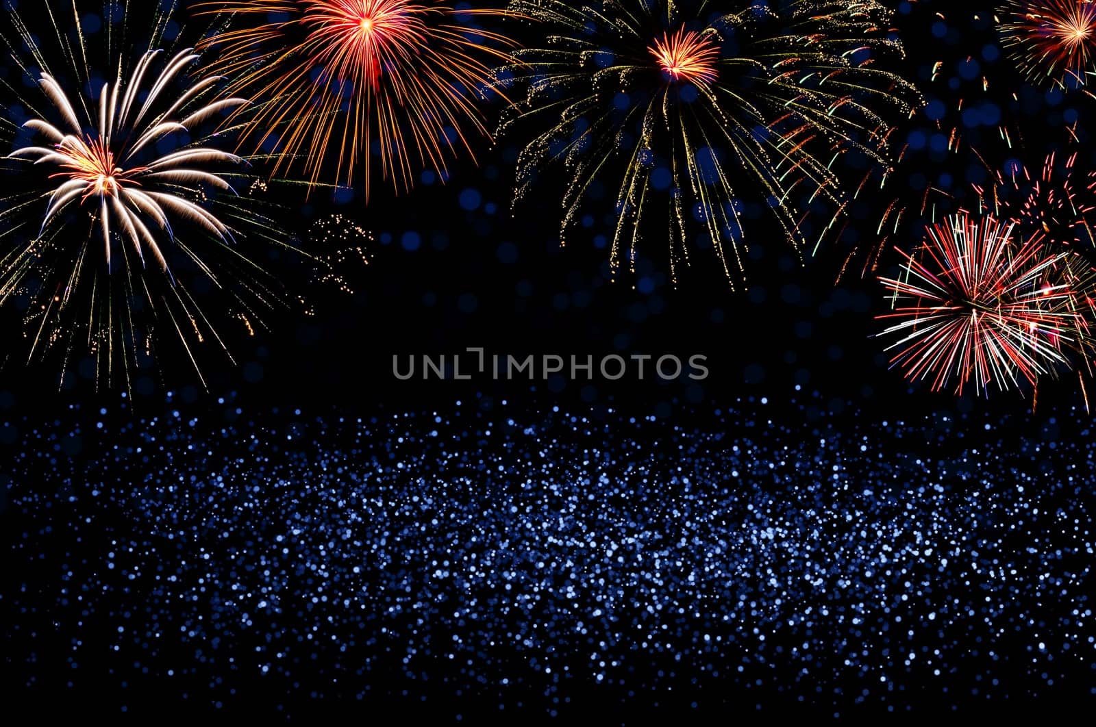 Colorful fireworks on blue glitter background with copy space. New Year celebration and holiday concept