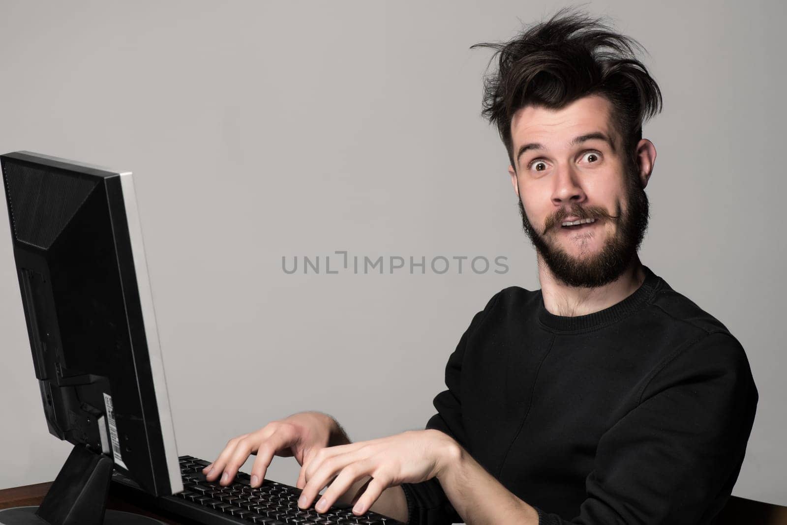 Funny and crazy man using a computer on gray background. man&#39 s hands on the keyboard