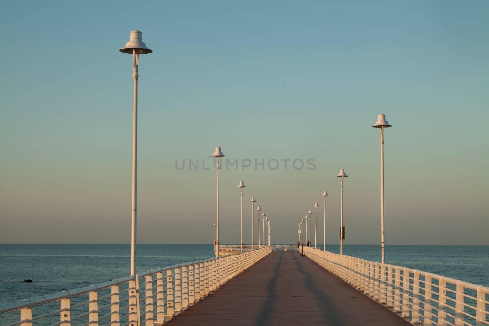 Sequence of lamps alternating with a sense of infinity of a marine pier of Marina of Massa