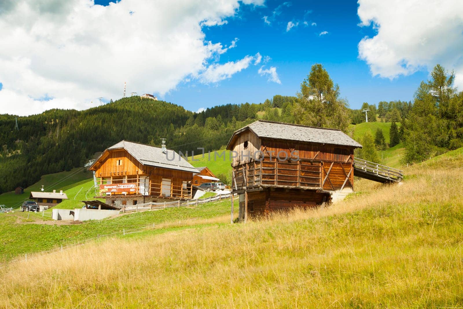 A refuge and a restaurant in nearby high Badia on green grass with blue sky and white clouds