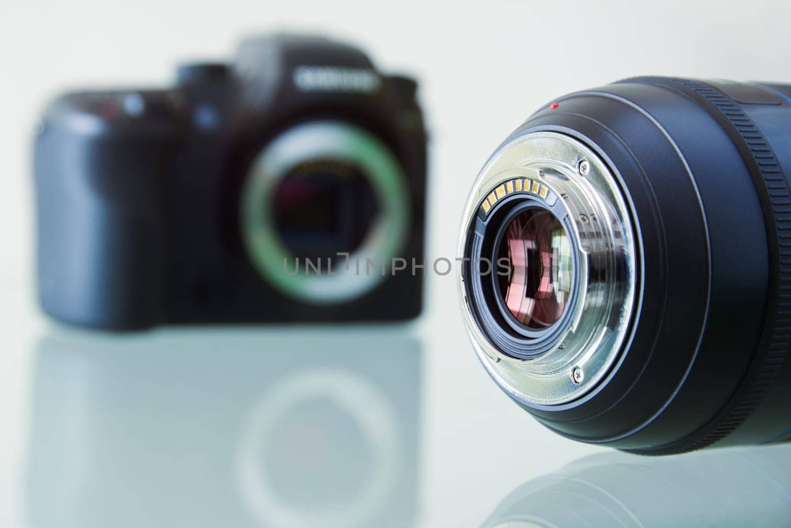 Still life of dslr camera and photo lens on glass table. Closeup of electronic circuit, rear glass and mount with copyspace in foreground