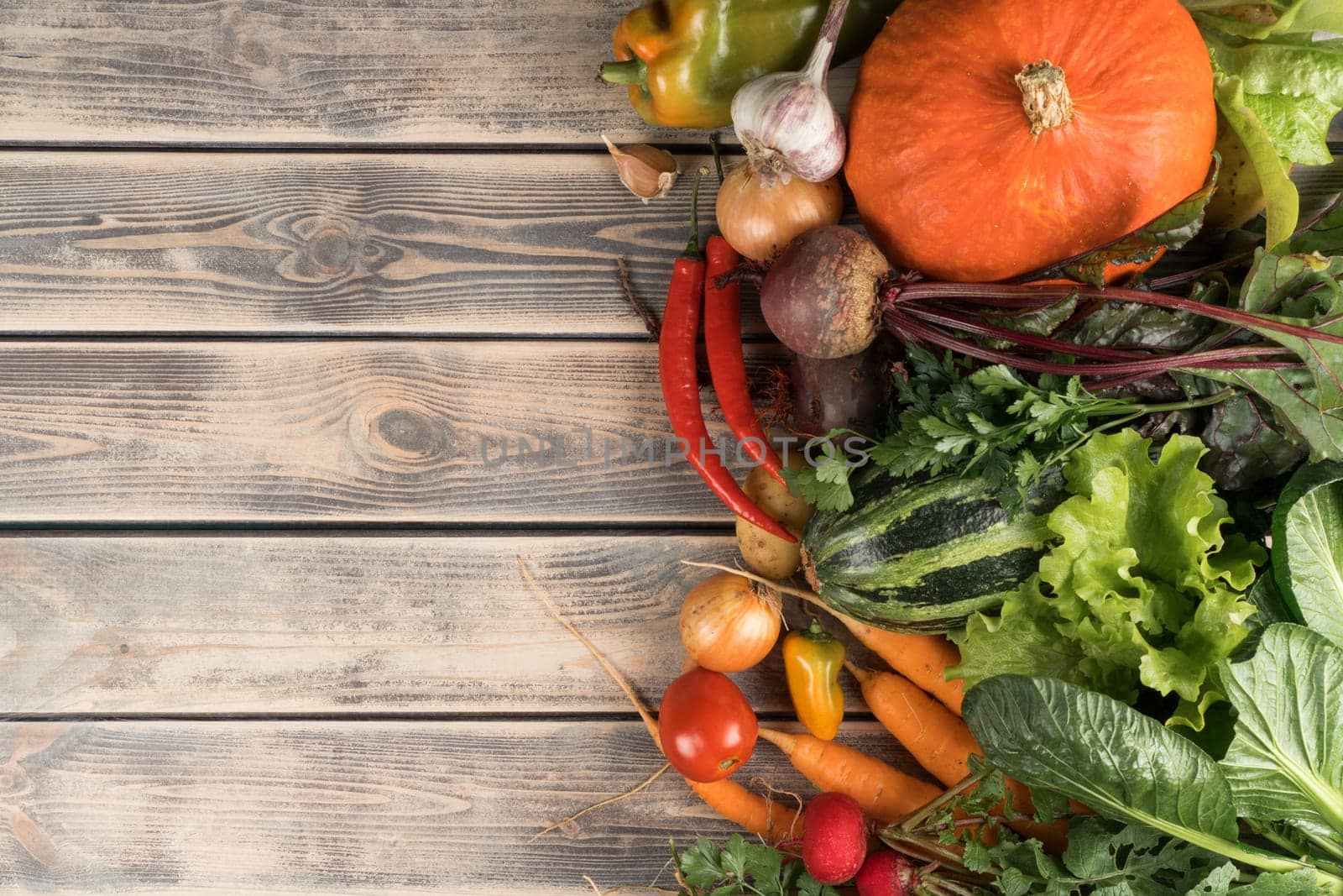 Colorful mix of fresh vegetables, top view. Sorting of organic seasonal harvest on wooden table. Nitrate free food or healthy diet concept. Balanced nutrition. Cooking ingredients. Place for text.