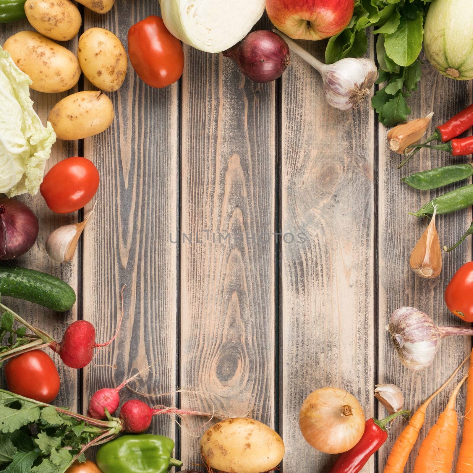 Colorful mix of fresh farm vegetables and fruits, top view. Wooden table of organic ripe seasonal harvest. Nitrate free food or healthy diet concept. Objects circular arrangement. Planking.