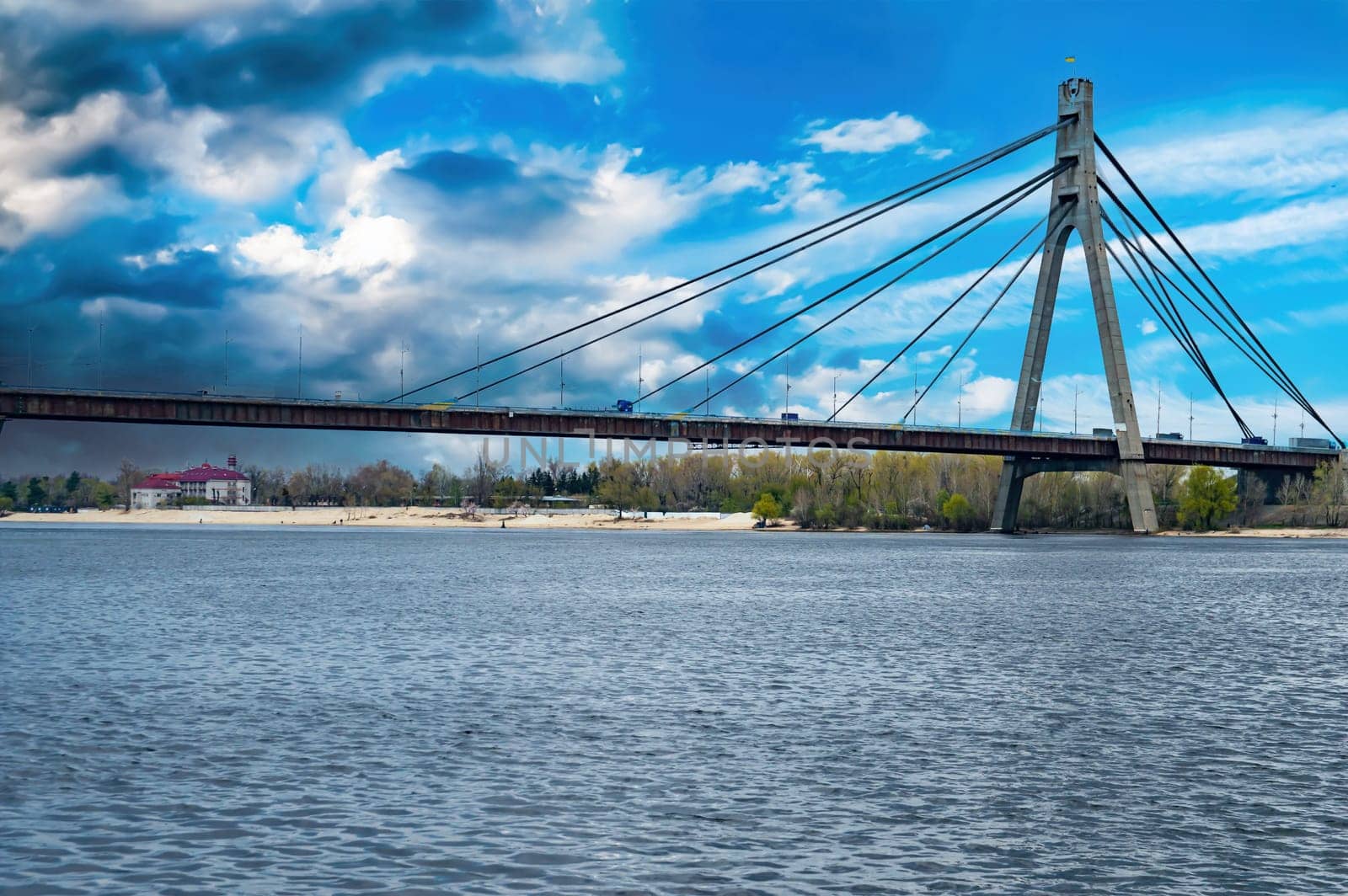 Bridge over the Dnieper River in Kiev against a cloudy sky. Car crossing over water. Bridge over the river. Water flow. Blue sky. Thunderclouds. Background. Industrial architecture.