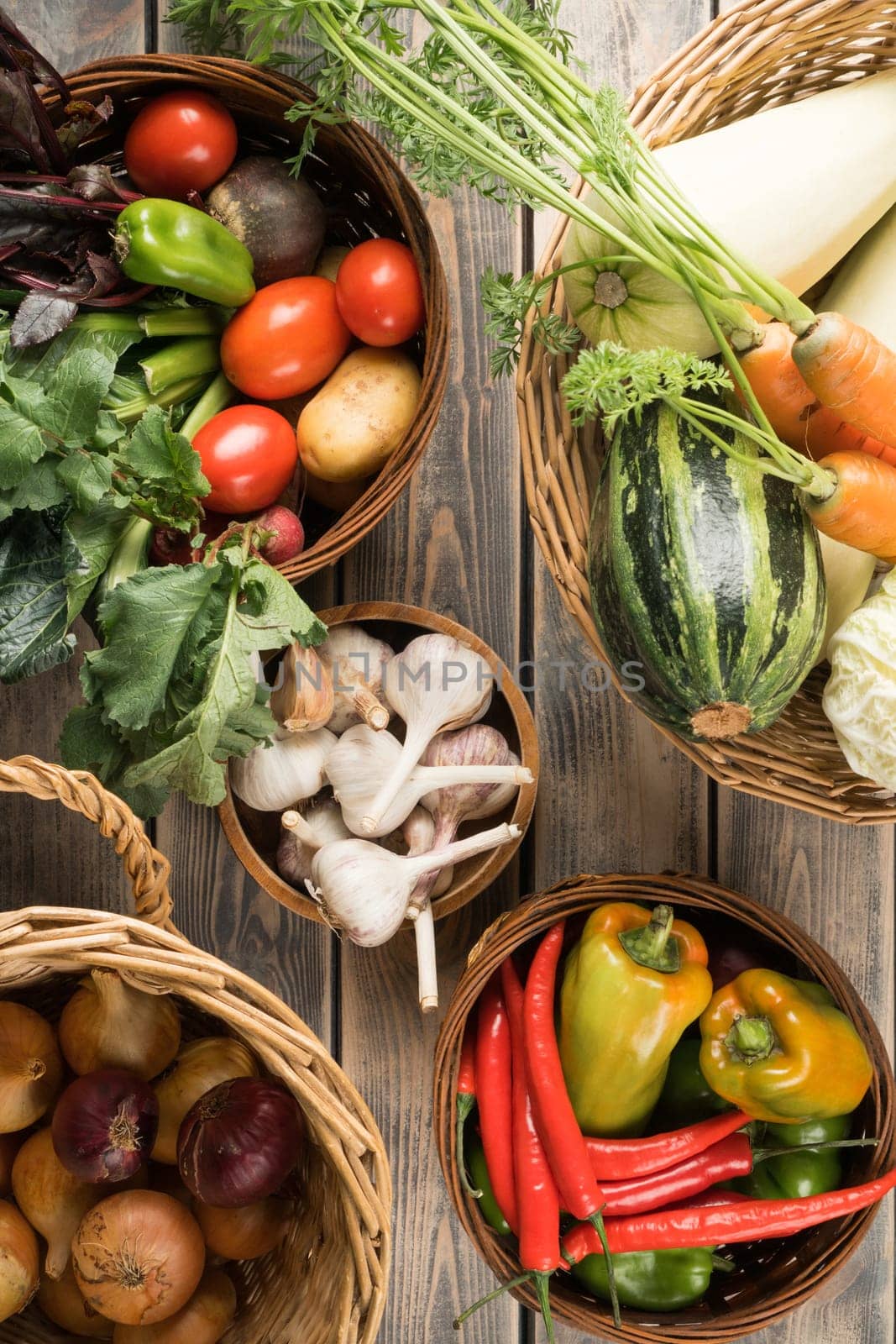 Wicker baskets with different fresh garden vegetables on wooden table, top view. Bowls full of organic ripe harvest. Food or healthy diet concept. Nitrate free nutrition. Cooking ingredients.