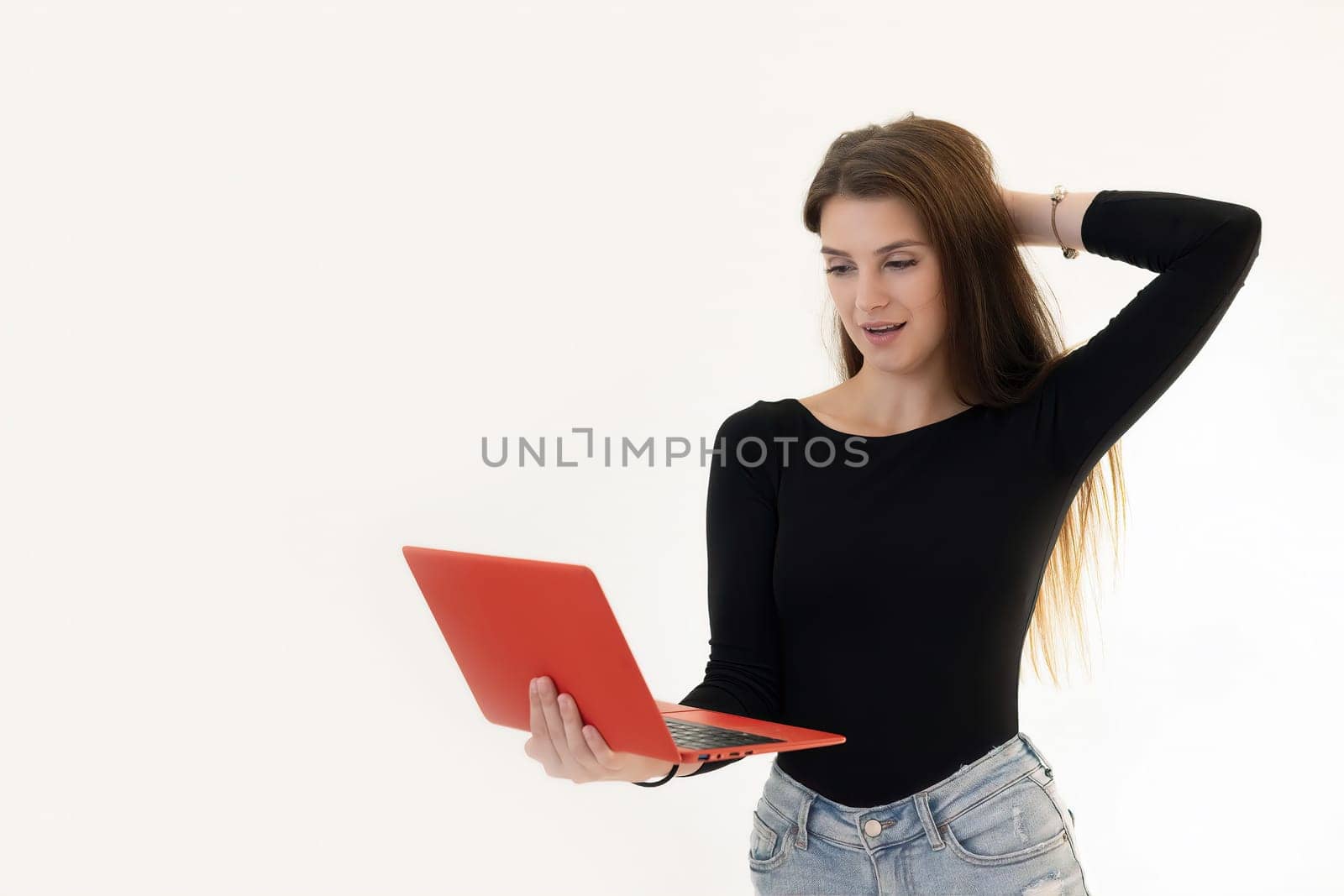 Surprised charming young woman holding laptop in hand. Isolated on white background.