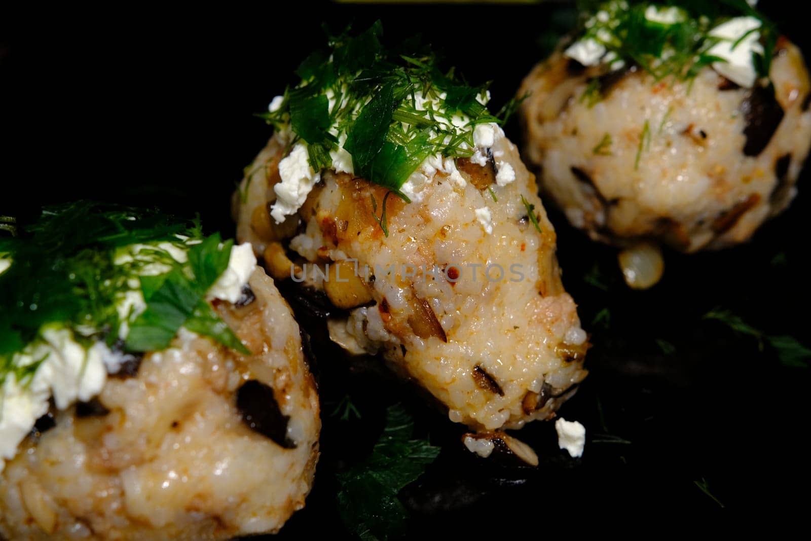 Japanese food, meat and oyster mushroom rice ball with green on top of the cheese on black background.