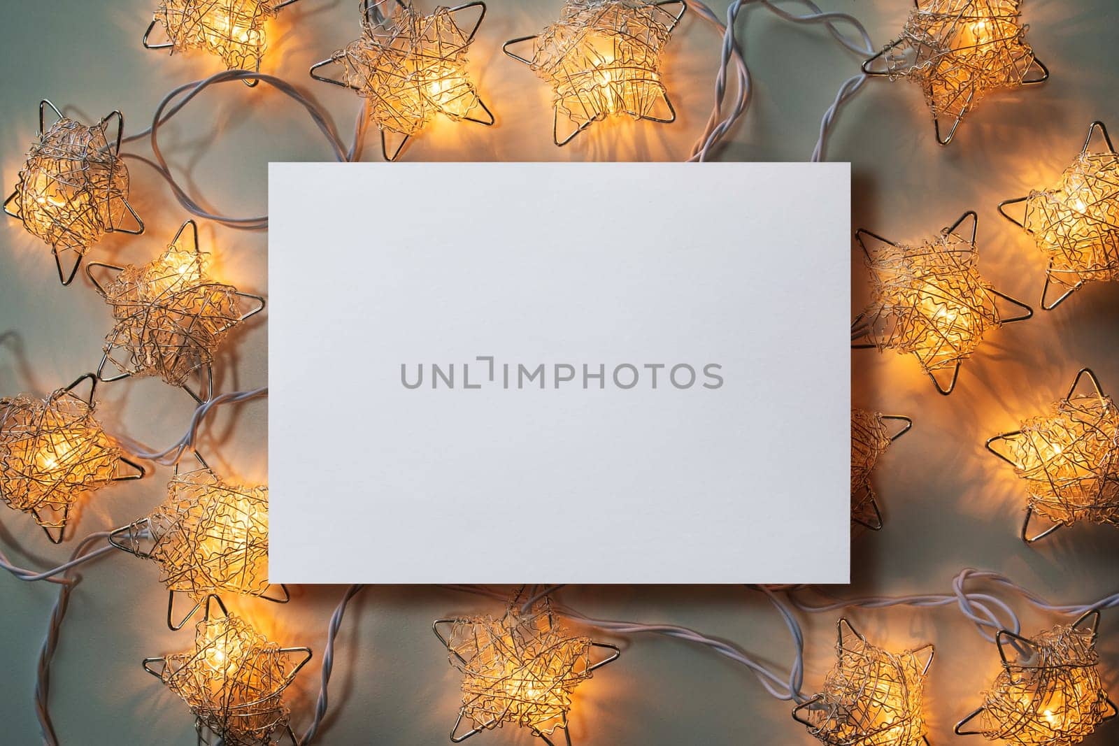 Christmas winter festive ornament. Blank paper card  and Christmas lights decoration background. Invitation Christmas holiday party. Flat lay, top view, copy space.