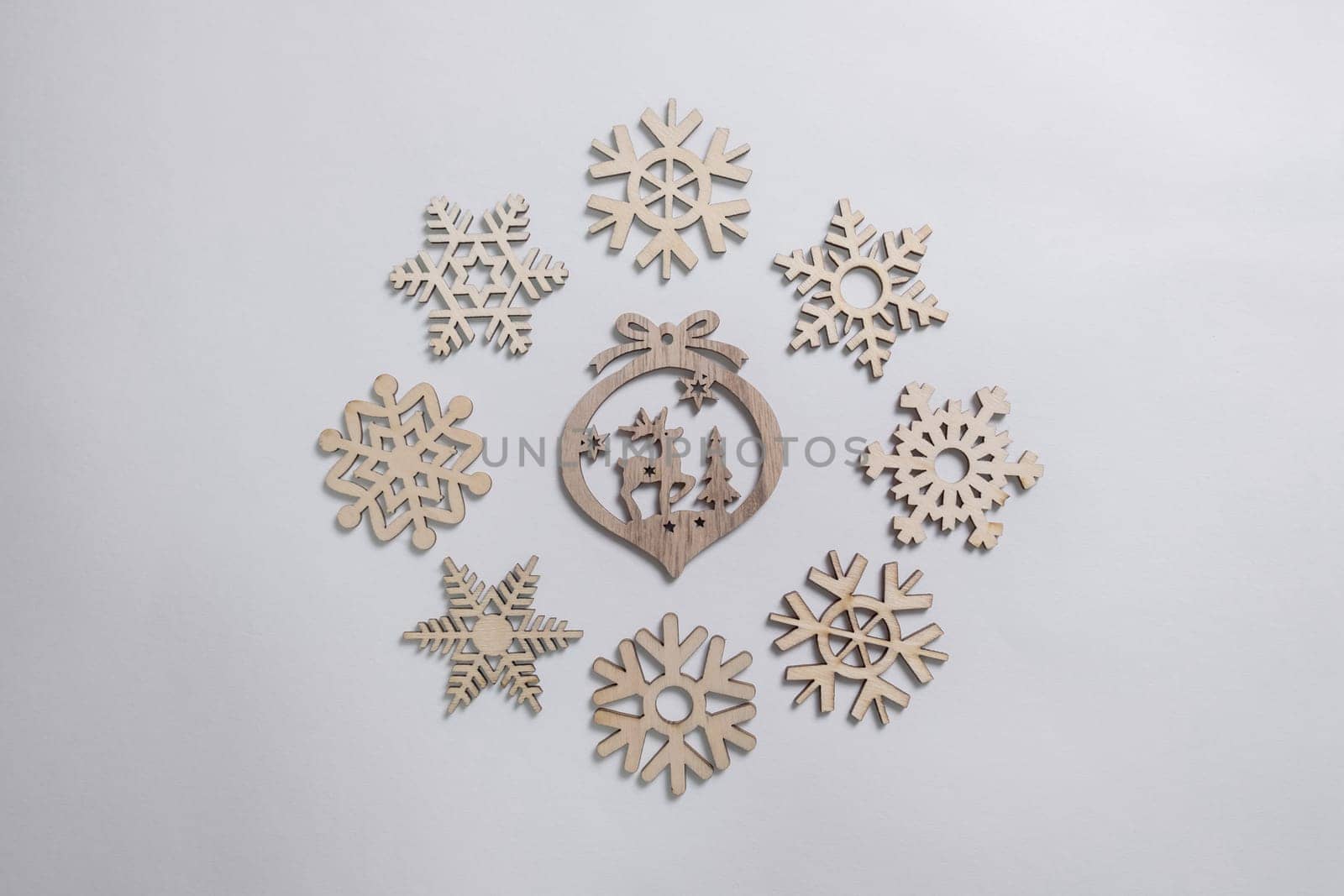 Christmas winter festive ornament. Christmas snowflakes and wooden decoration on white background. Christmas holiday decoration. Minimal holiday greeting season. Flat lay, top view.