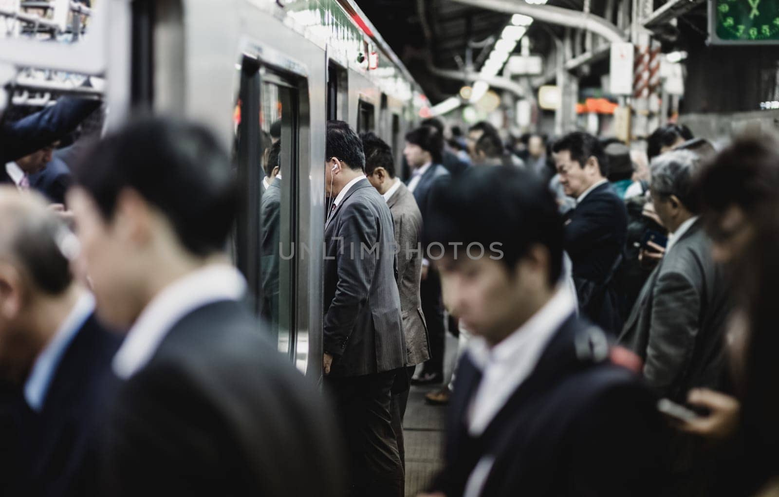 Passengers traveling by Tokyo metro. Business people commuting to work by public transport in rush hour. Shallow depth of field photo.