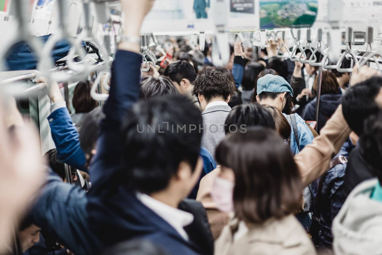 Passengers traveling by Tokyo metro. Business people commuting to work by public transport in rush hour. Shallow depth of field photo. Horizontal composition.