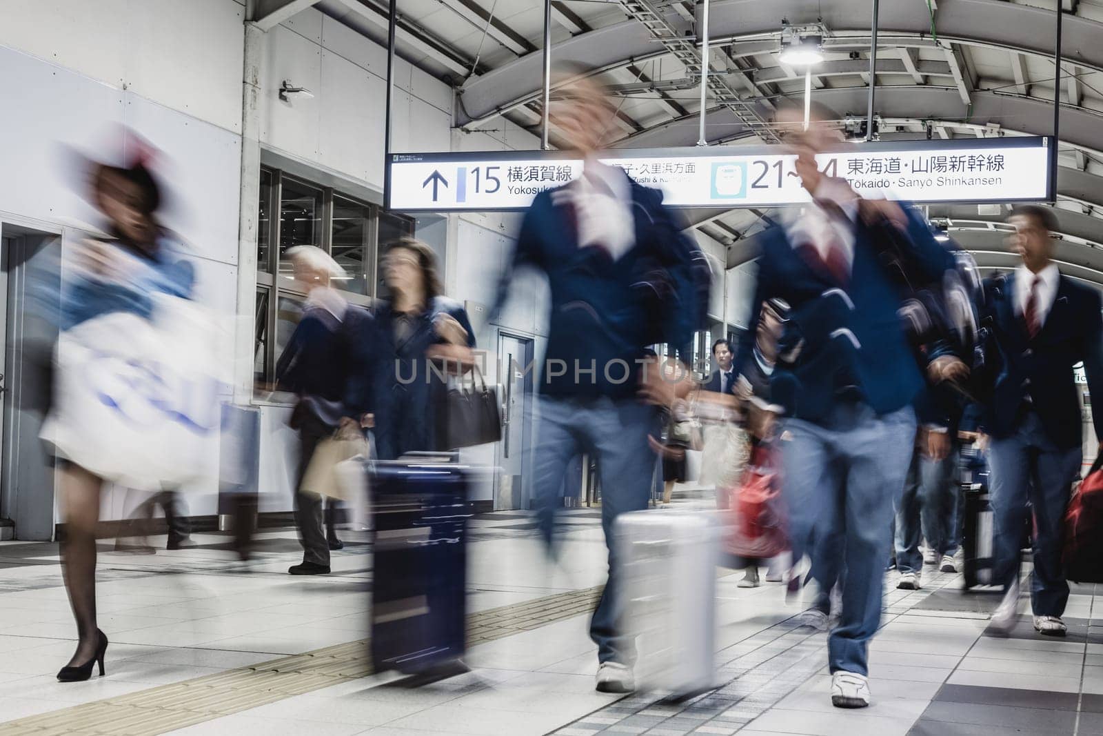 Corporate business people commuting to work by Tokyo public transport. Unrecognizable people blured in motion while rushing to train platforms.