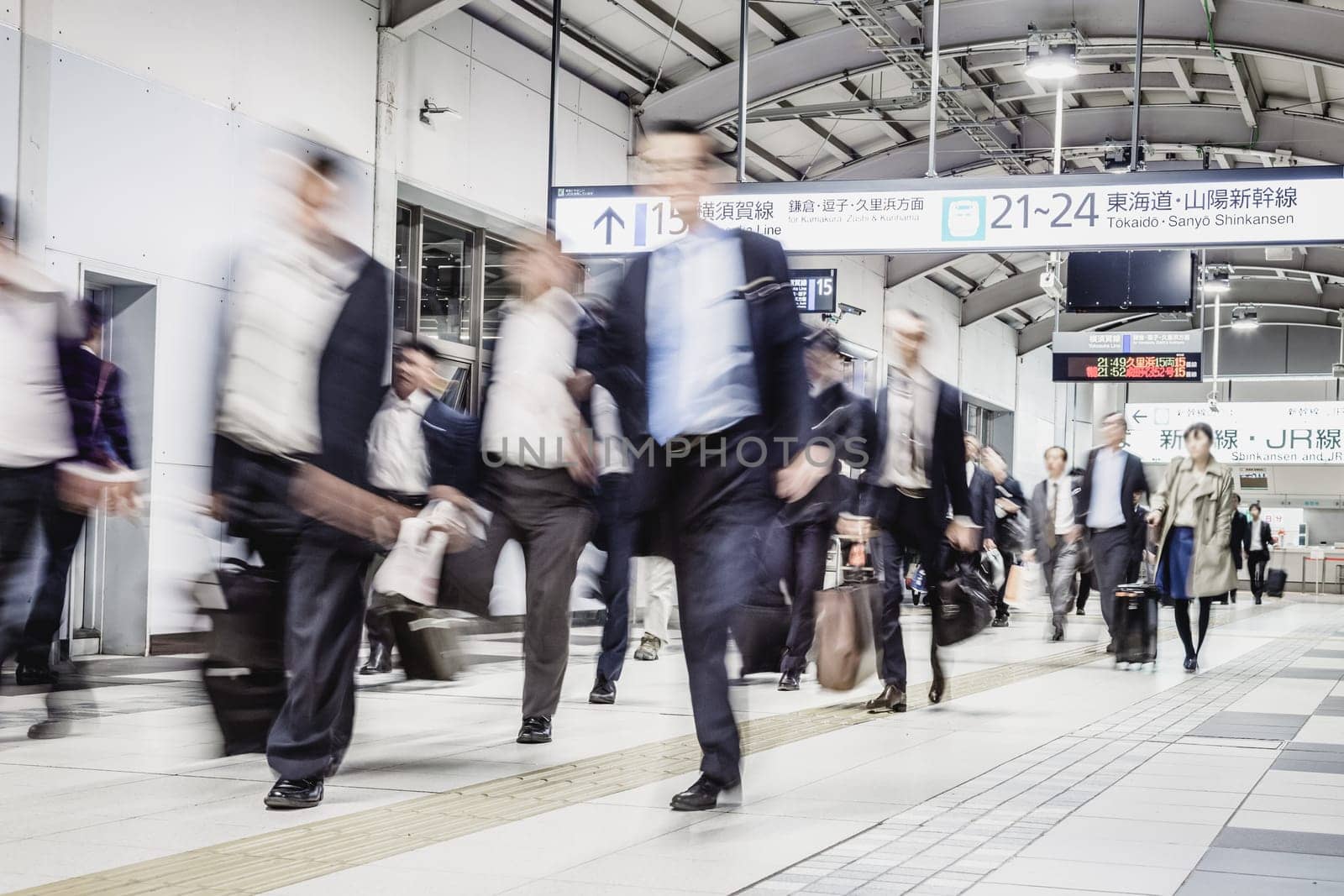 Corporate business people commuting to work by Tokyo public transport. Unrecognizable people blured in motion while rushing to train platforms.