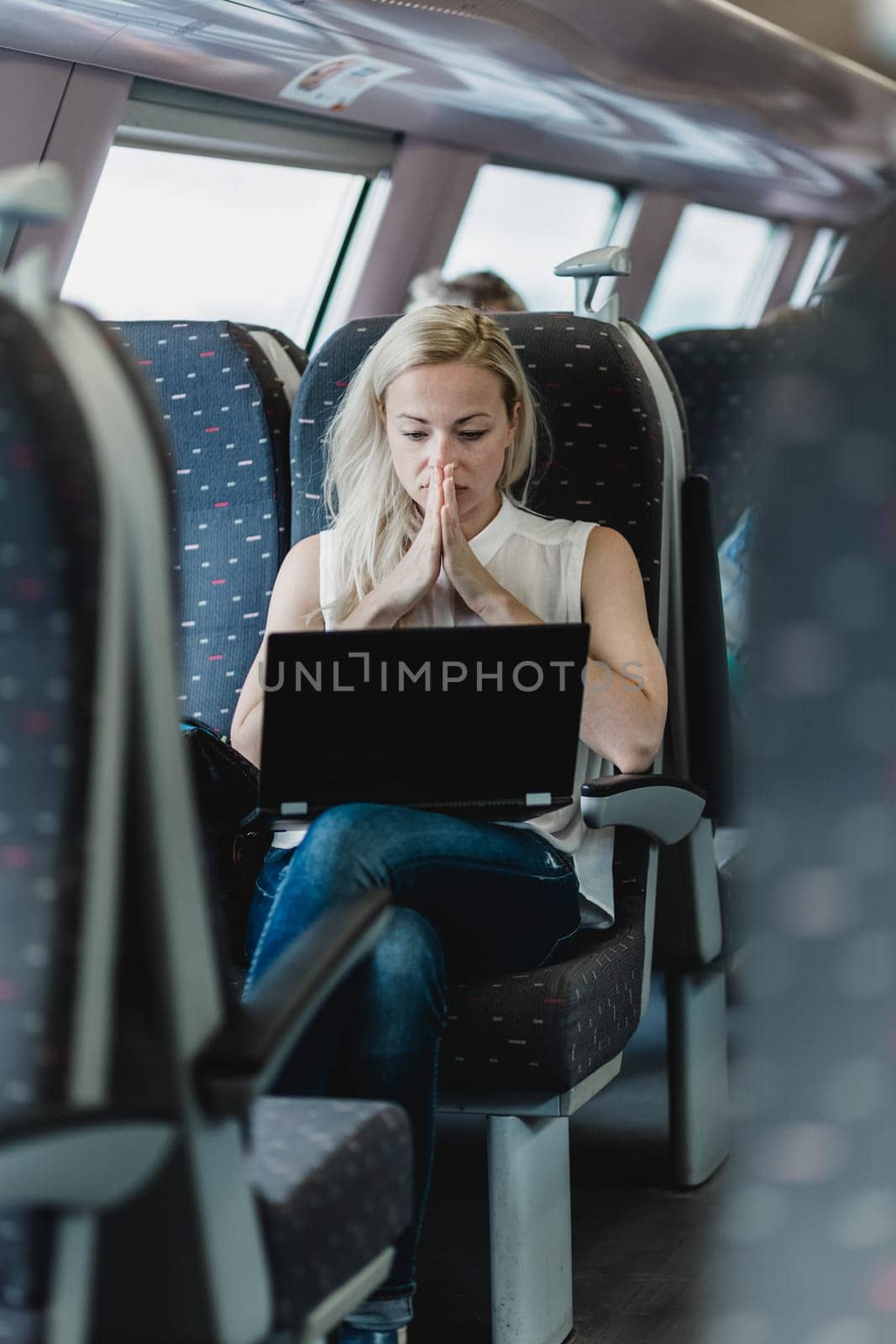 Businesswoman sitting and traveling by train working on laptop.