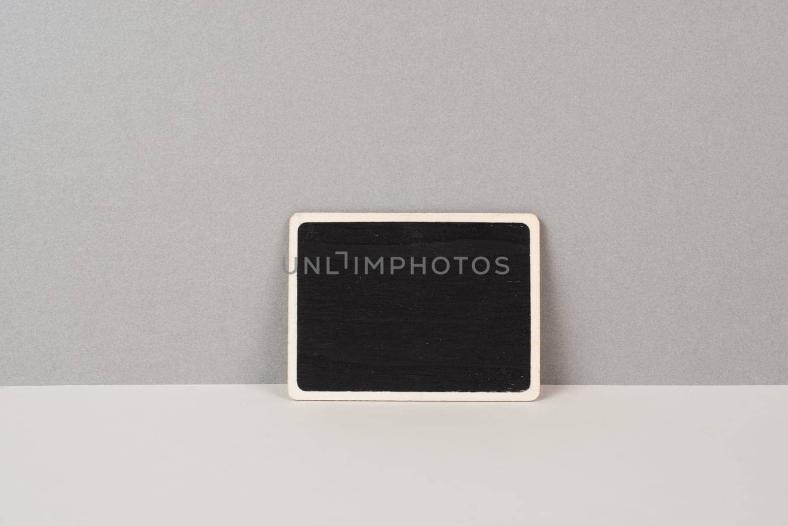 Black chalkboard sign on a gray background, copy space for text, minimalism