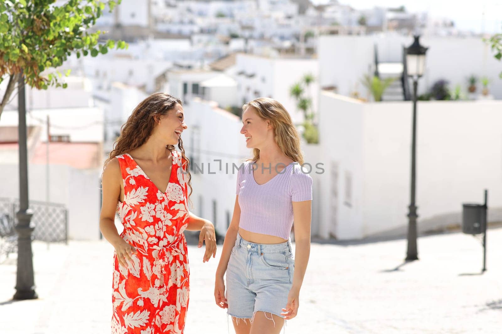 Two friends talking in the street in a white town on summer vacation