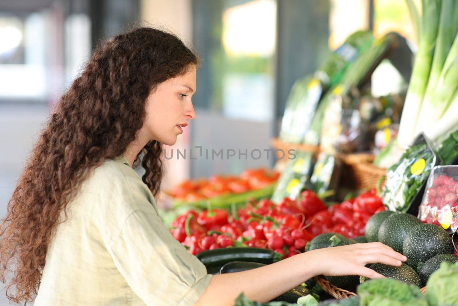 Woman buying and choosing vegetables in a greengrocery