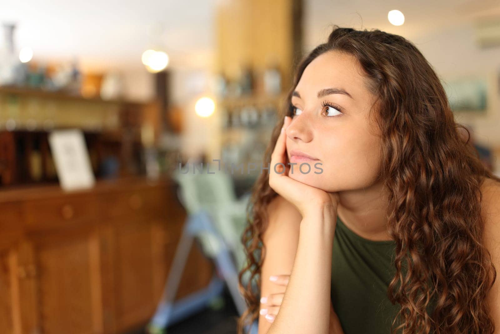 Distracted and pensive woman looking away in a restaurant