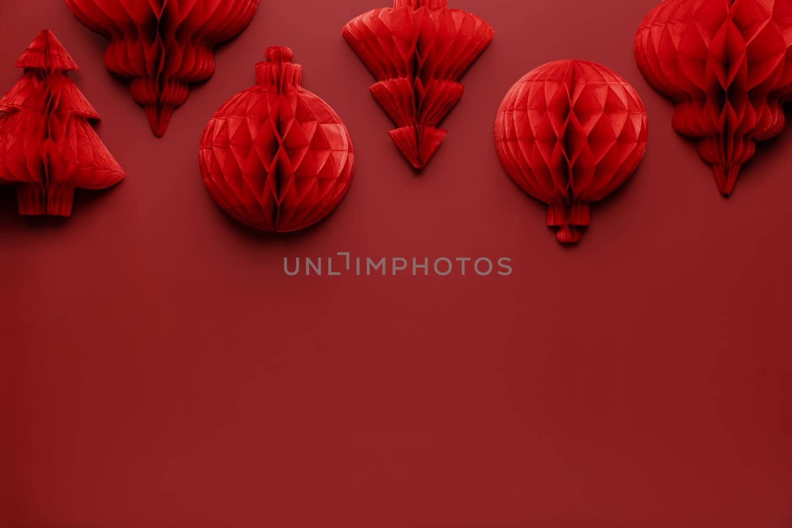 Christmas or New Year background. Red burgundy color flat lay with decorations. Copy space area for advertising or marketing text. Paper balls and fit trees. Simple minimalistic greeting card mockup