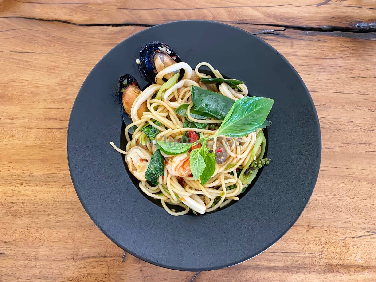 Drunken seafood spaghetti in a black plate.