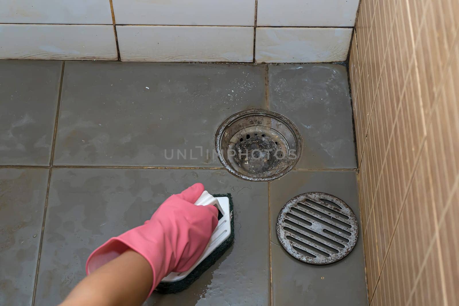 Woman cleaning bathroom floor that is very dirty.